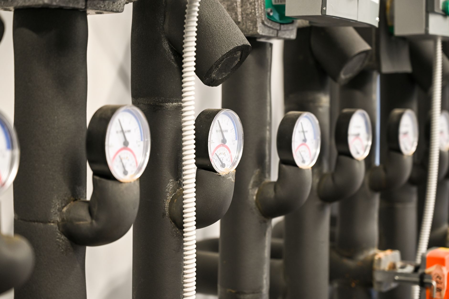 close-up of an oil pipeline junction with valves and pressure gauges in a flat industrial landscape under overcast skies