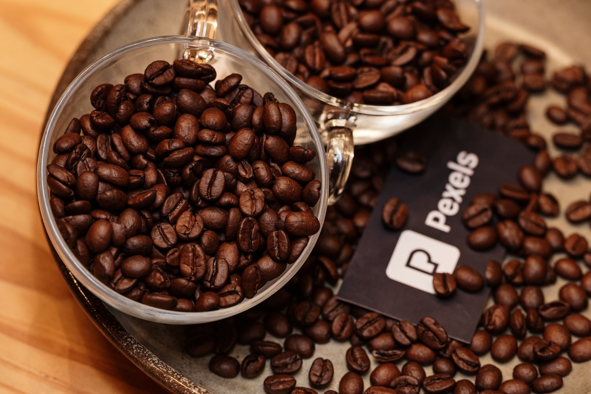 close-up of roasted decaffeinated coffee beans spread across a wooden surface in a specialty roastery, warm amber lighting