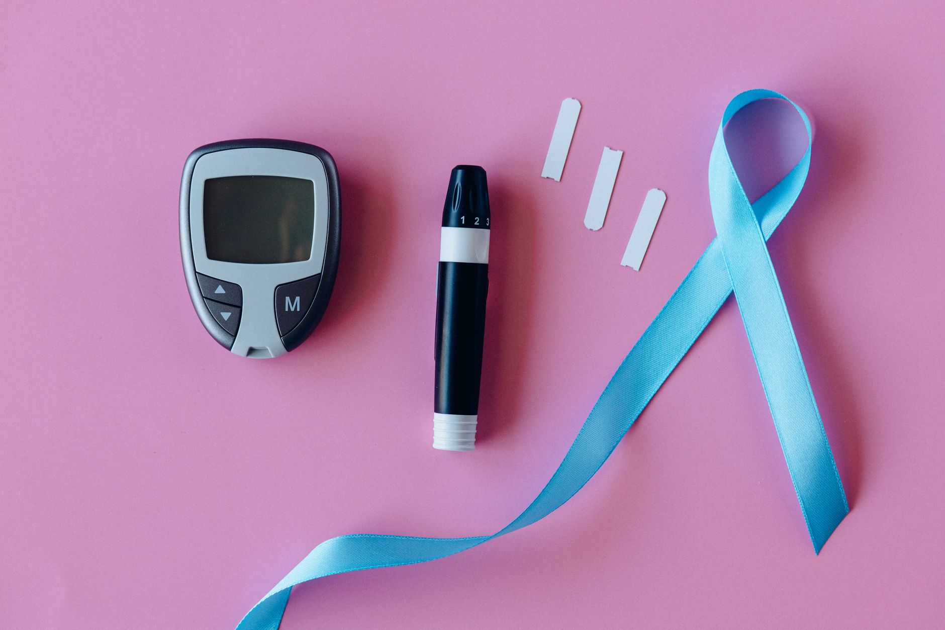close-up of a continuous glucose monitor device resting on a clinical desk beside a tablet displaying a patient data dashboard