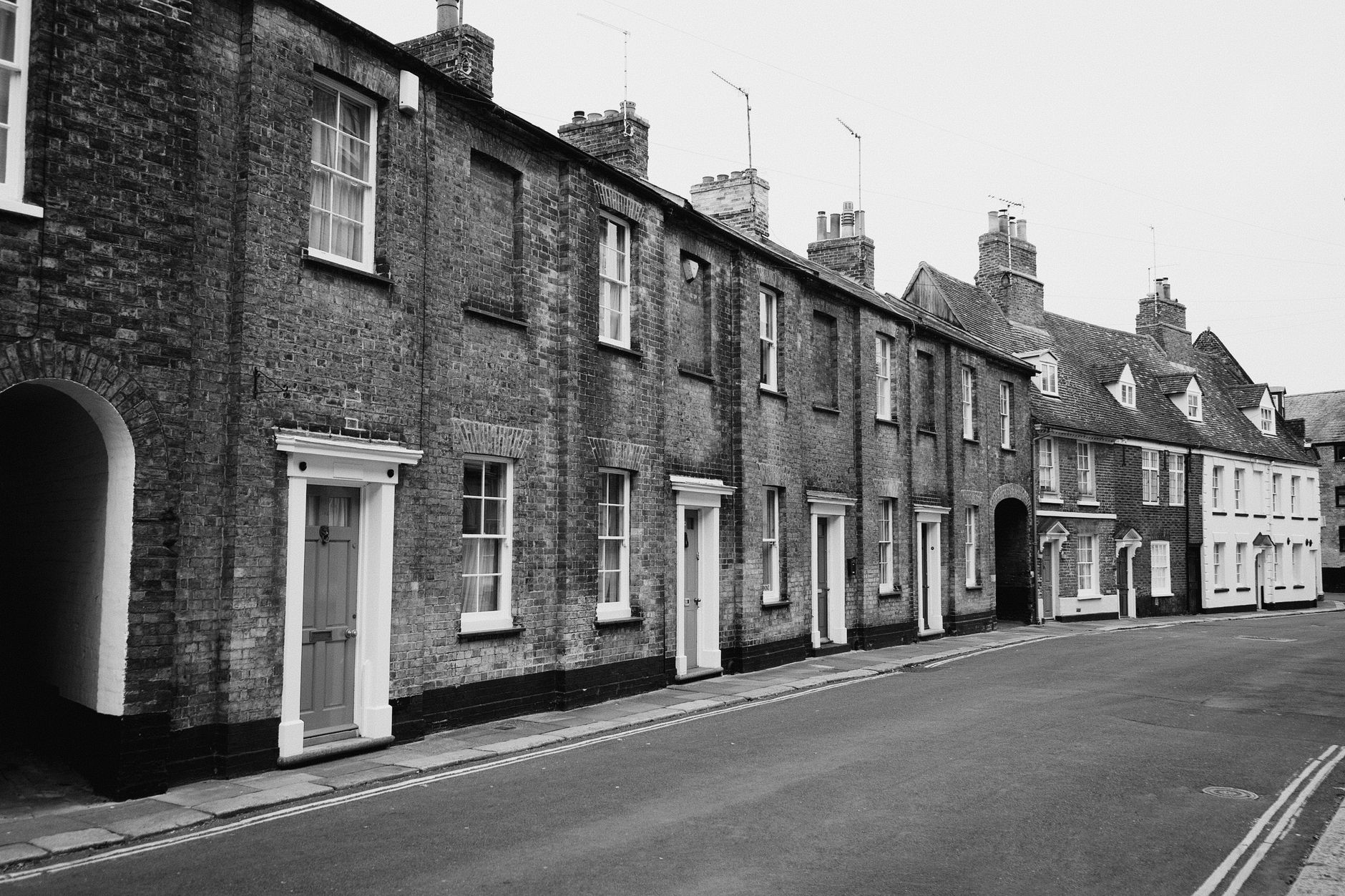 a row of terraced housing on a grey overcast day in a post-industrial UK town, with curtained windows and a quiet empty street