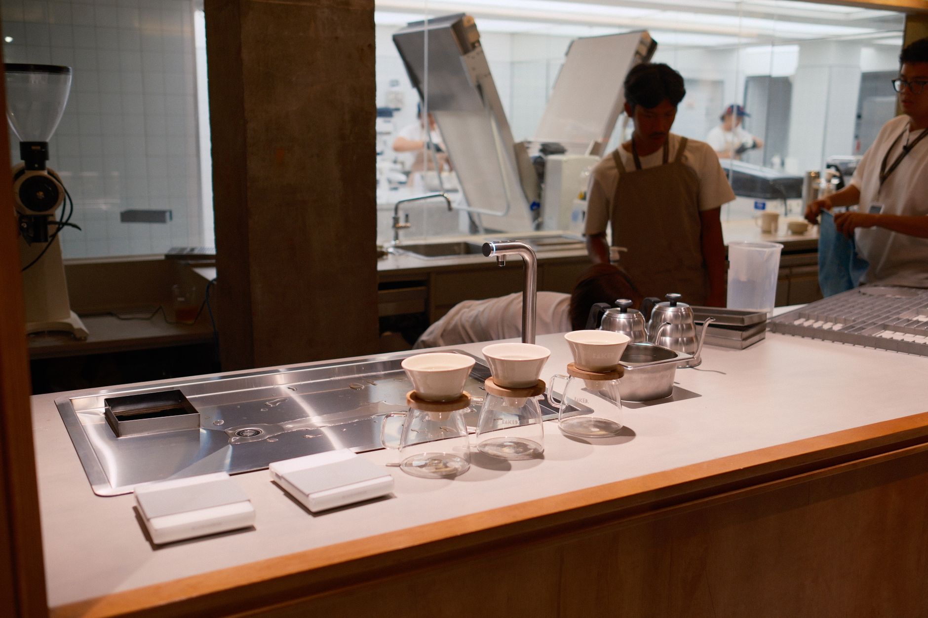 rows of unwashed reusable coffee cups stacked on a stainless steel commercial kitchen counter in a busy European cafe