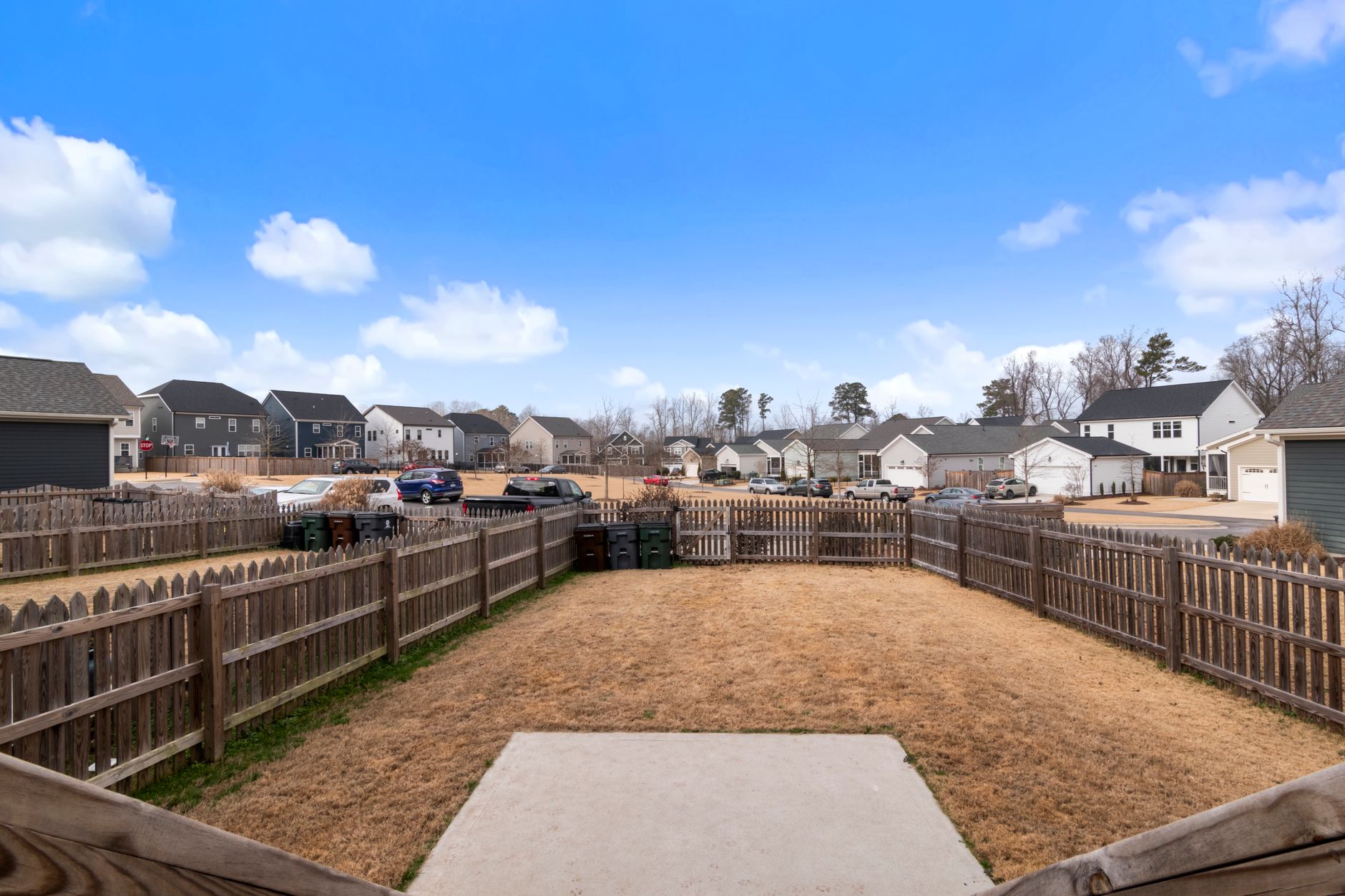 rows of empty new-build homes in a suburban development with for-sale signs visible, aerial perspective over a quiet cul-de-sac in afternoon light