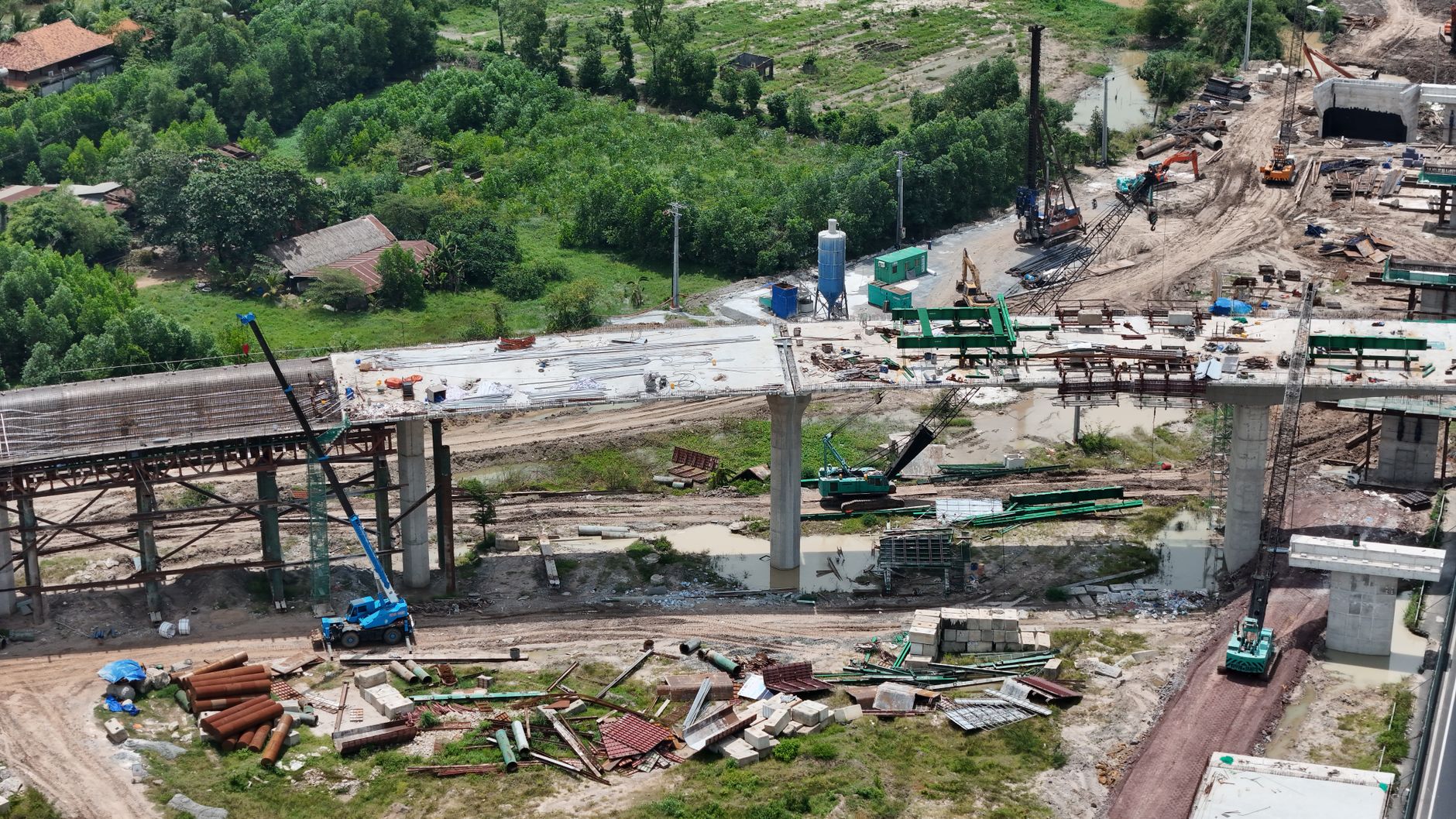aerial view of a large infrastructure construction site in an Indian metropolitan area, with cranes and partially completed elevated expressways visible at dusk
