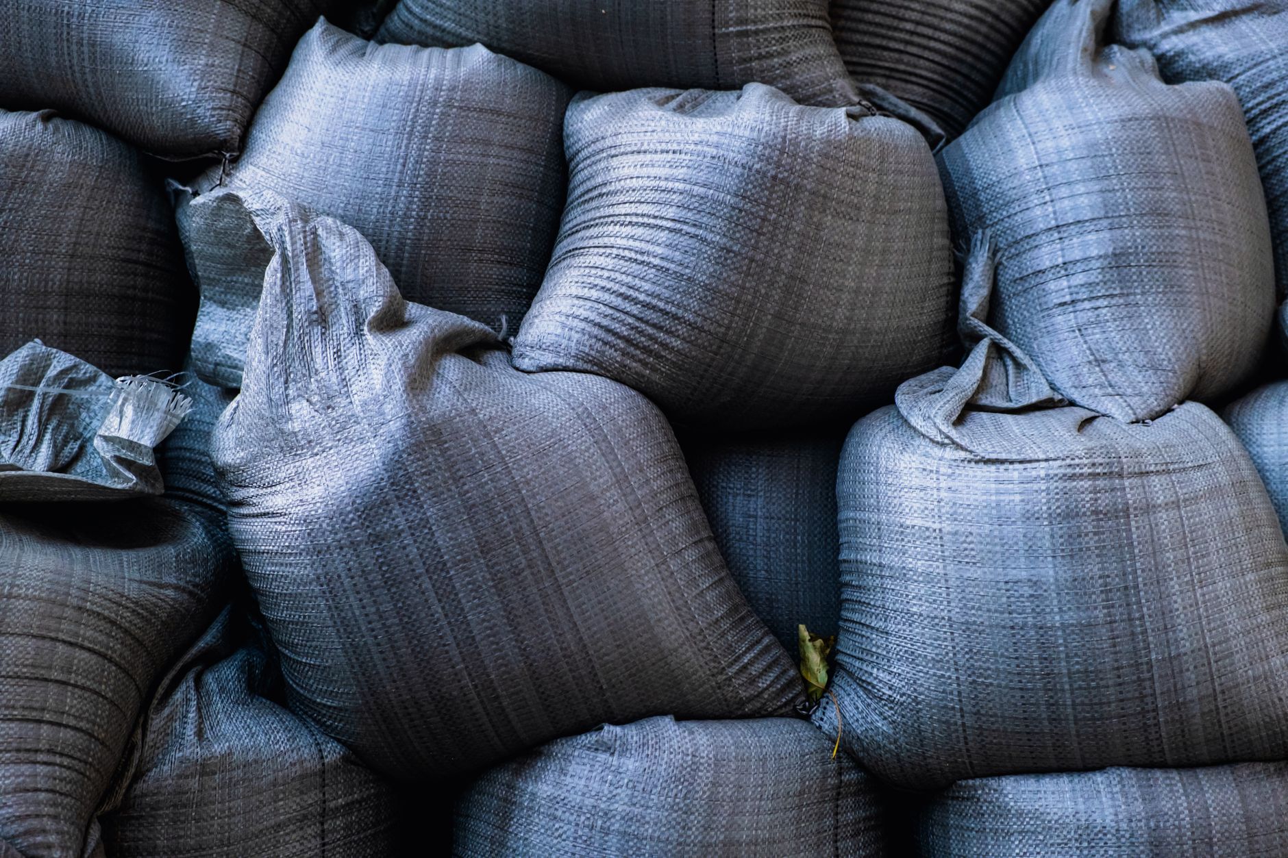 rows of grain sacks stacked inside a large government warehouse with visible price tags and storage labels