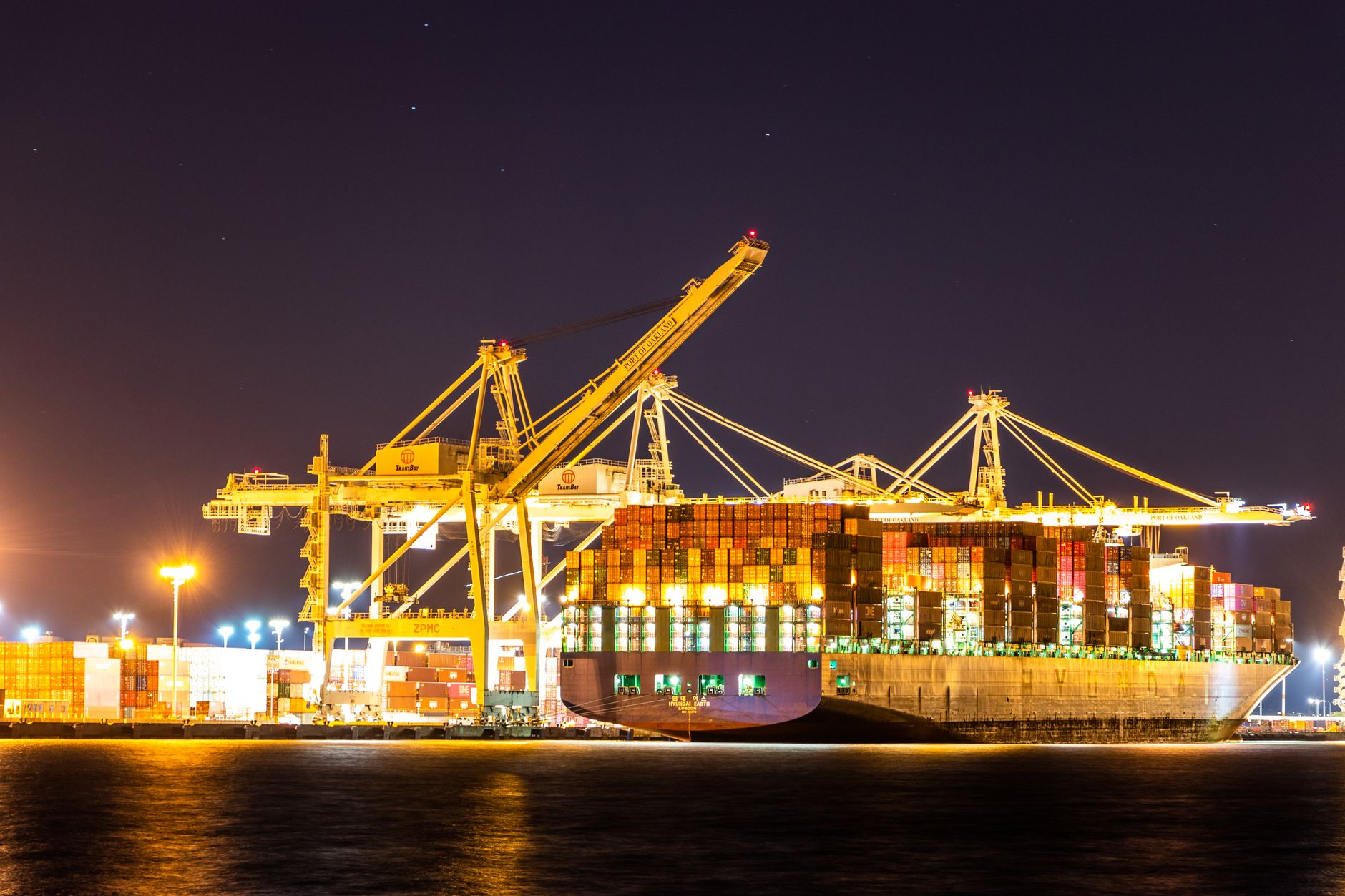 wide shot of a cargo vessel at sea loaded with multicolored shipping containers under an overcast sky
