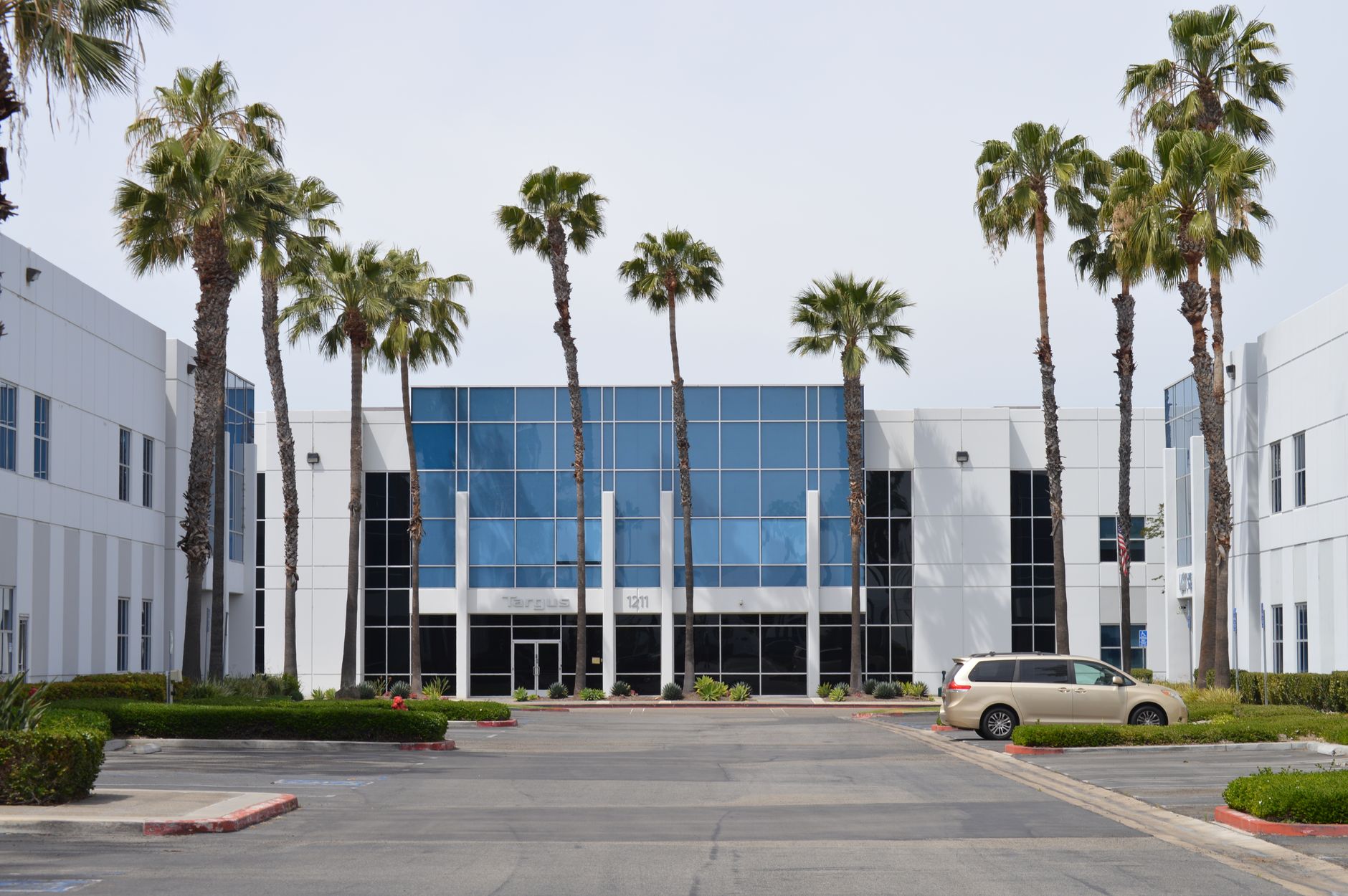 exterior of a mid-sized corporate office building on a clear day, with a modest parking lot and landscaped entrance in a suburban business district