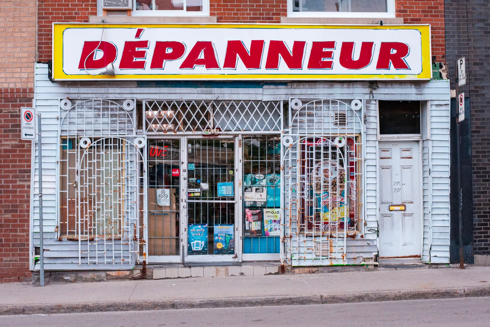 exterior of a shuttered small business storefront with a hand-painted sign, iron security gate pulled down, in a dense urban commercial district