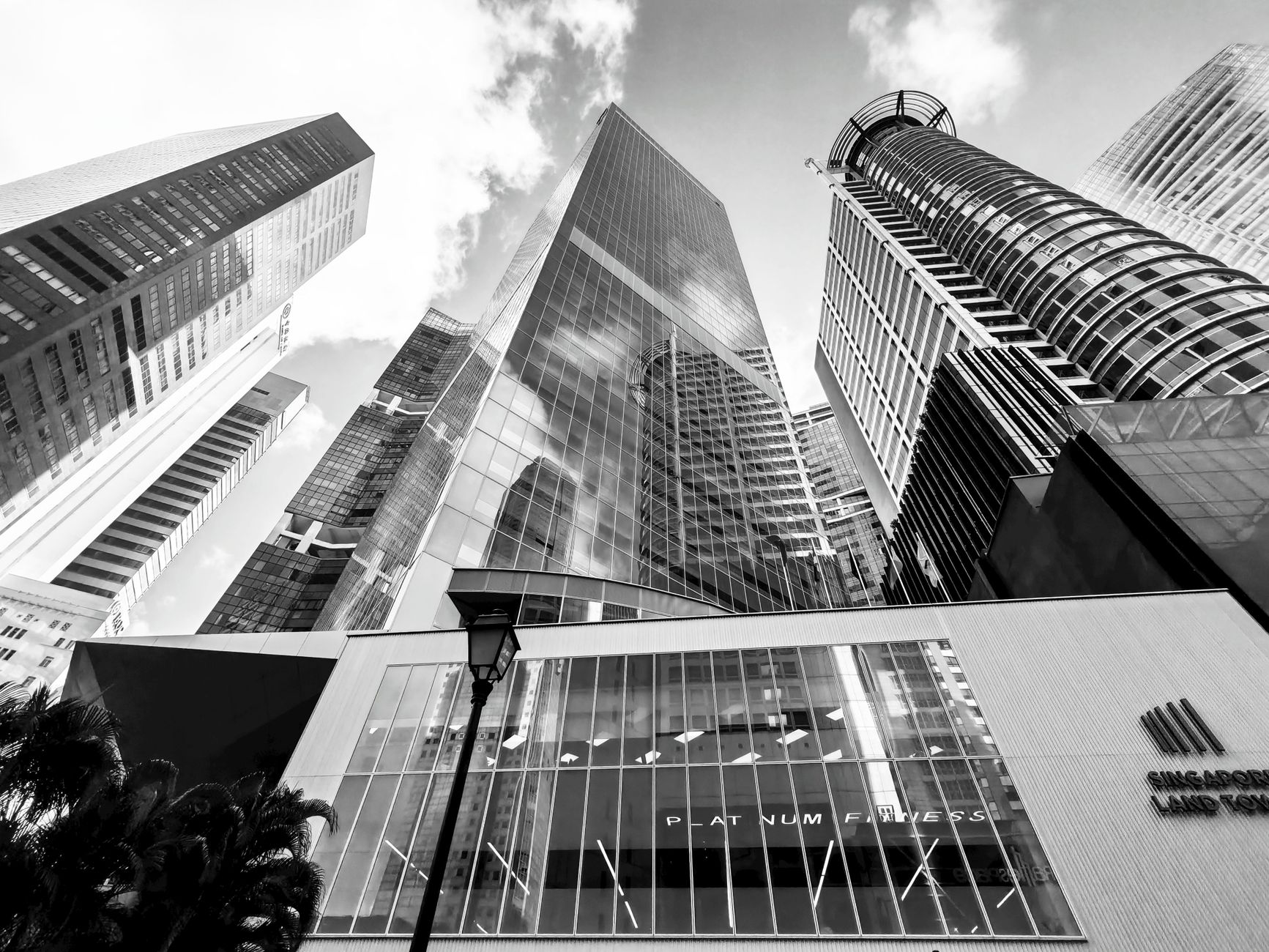 exterior view of a modern glass-fronted financial district office tower in Singapore's central business district at midday, reflecting the skyline