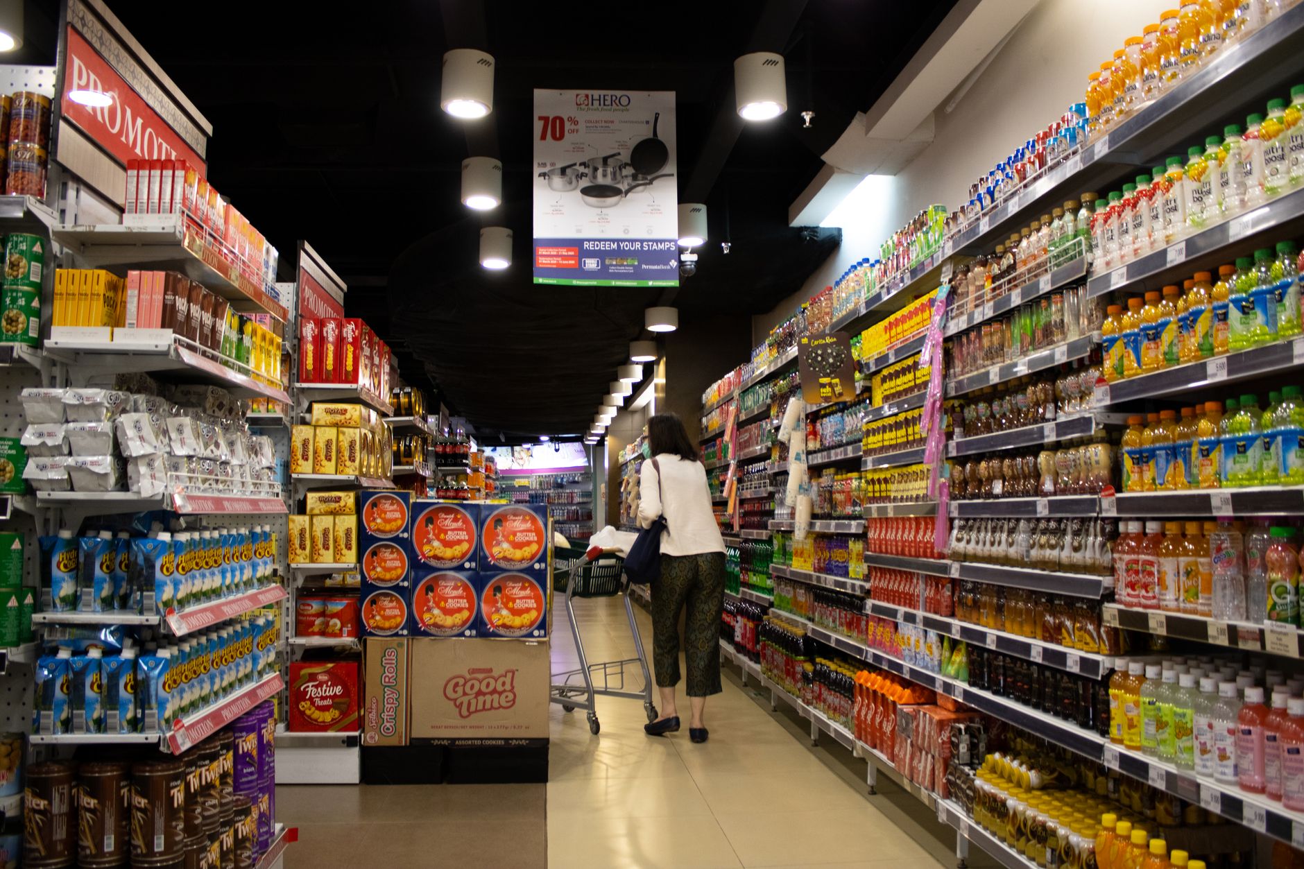 shelves of packaged consumer goods inside a modern Indian supermarket, with fluorescent lighting and price tags visible, no customers in frame