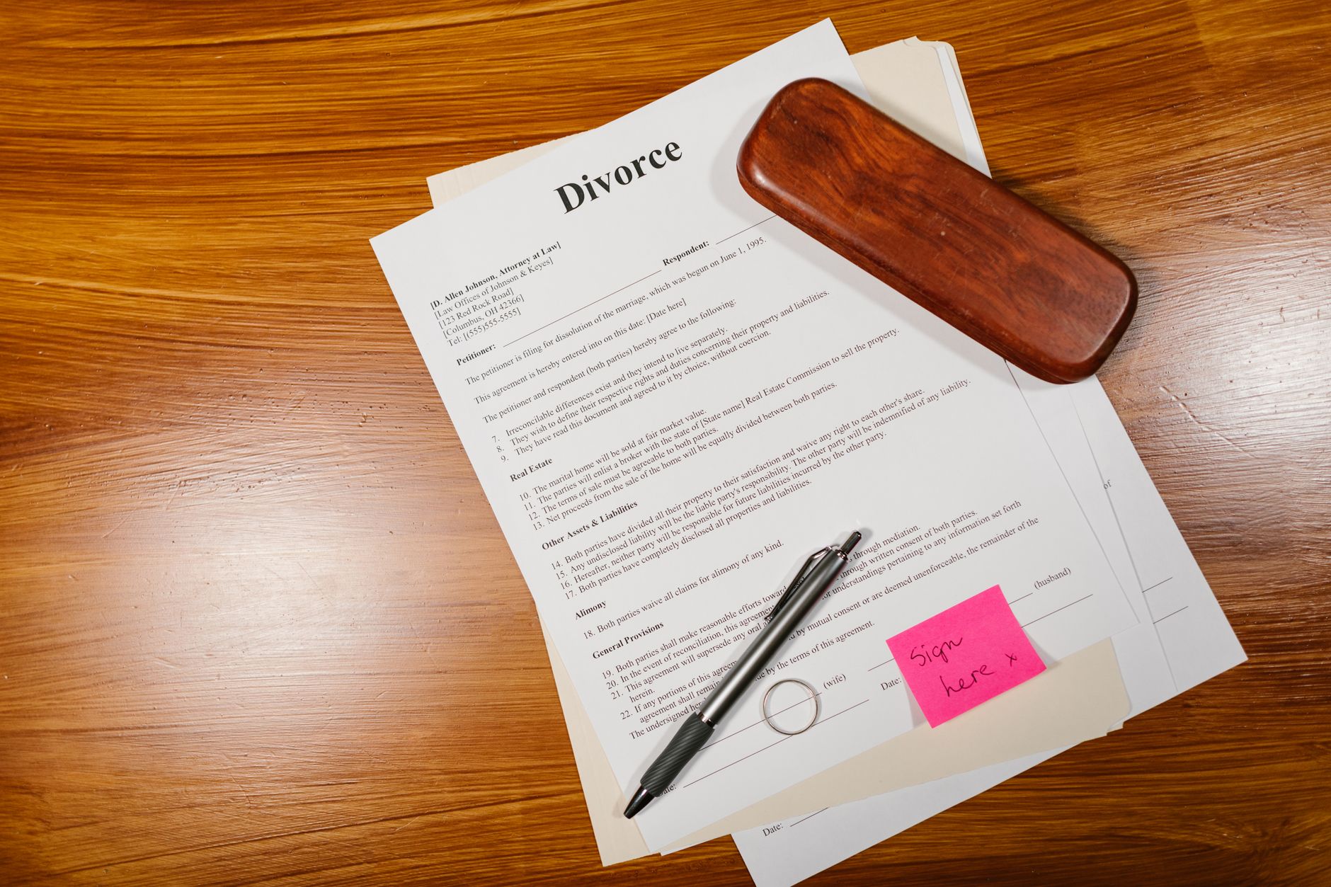 interior of a quiet legal office with a wooden desk covered in estate documents, a pen resting on a signature line, and a single lamp casting warm light