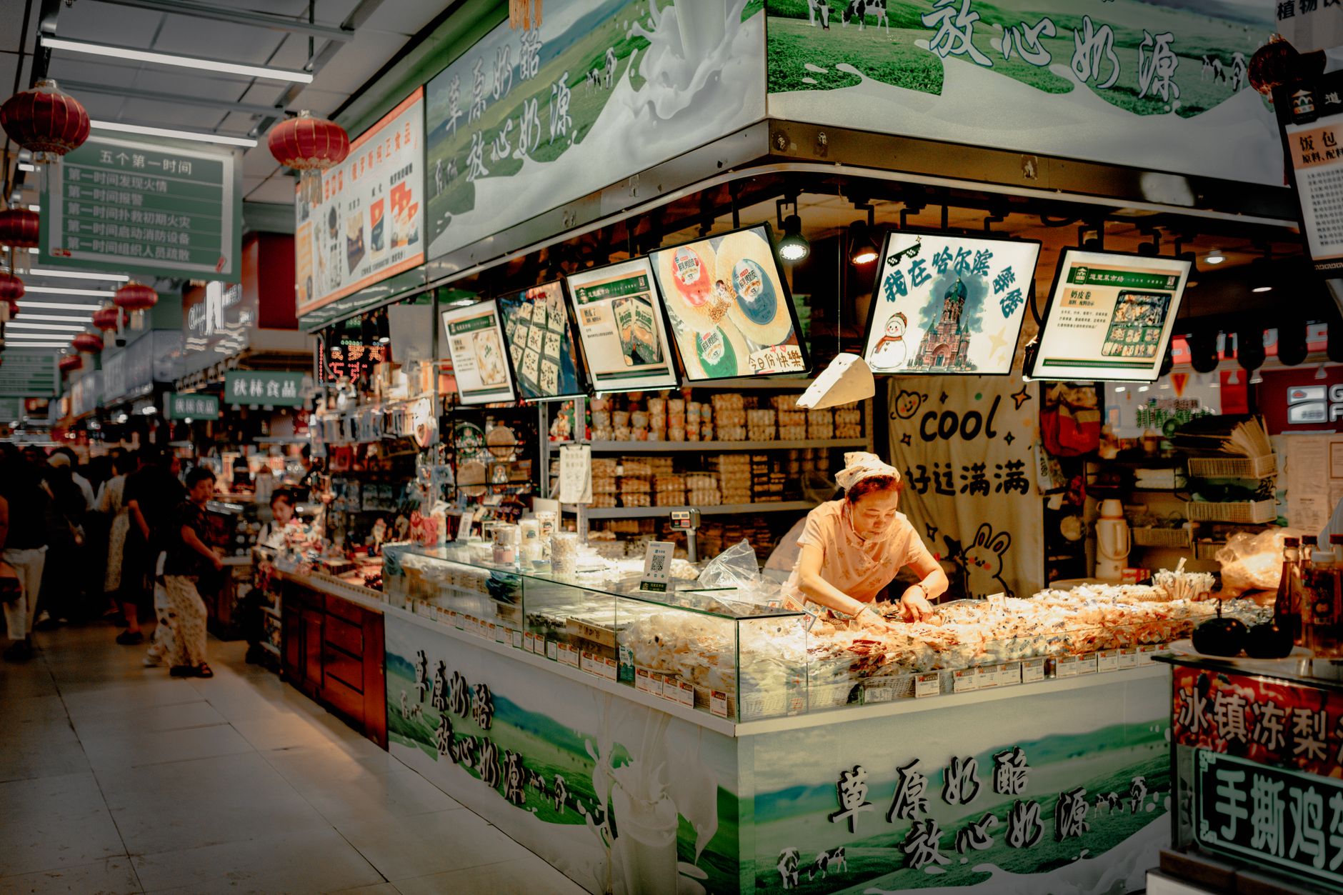 a busy indoor Israeli shopping mall concourse with storefronts lit up and payment terminals visible at checkout counters
