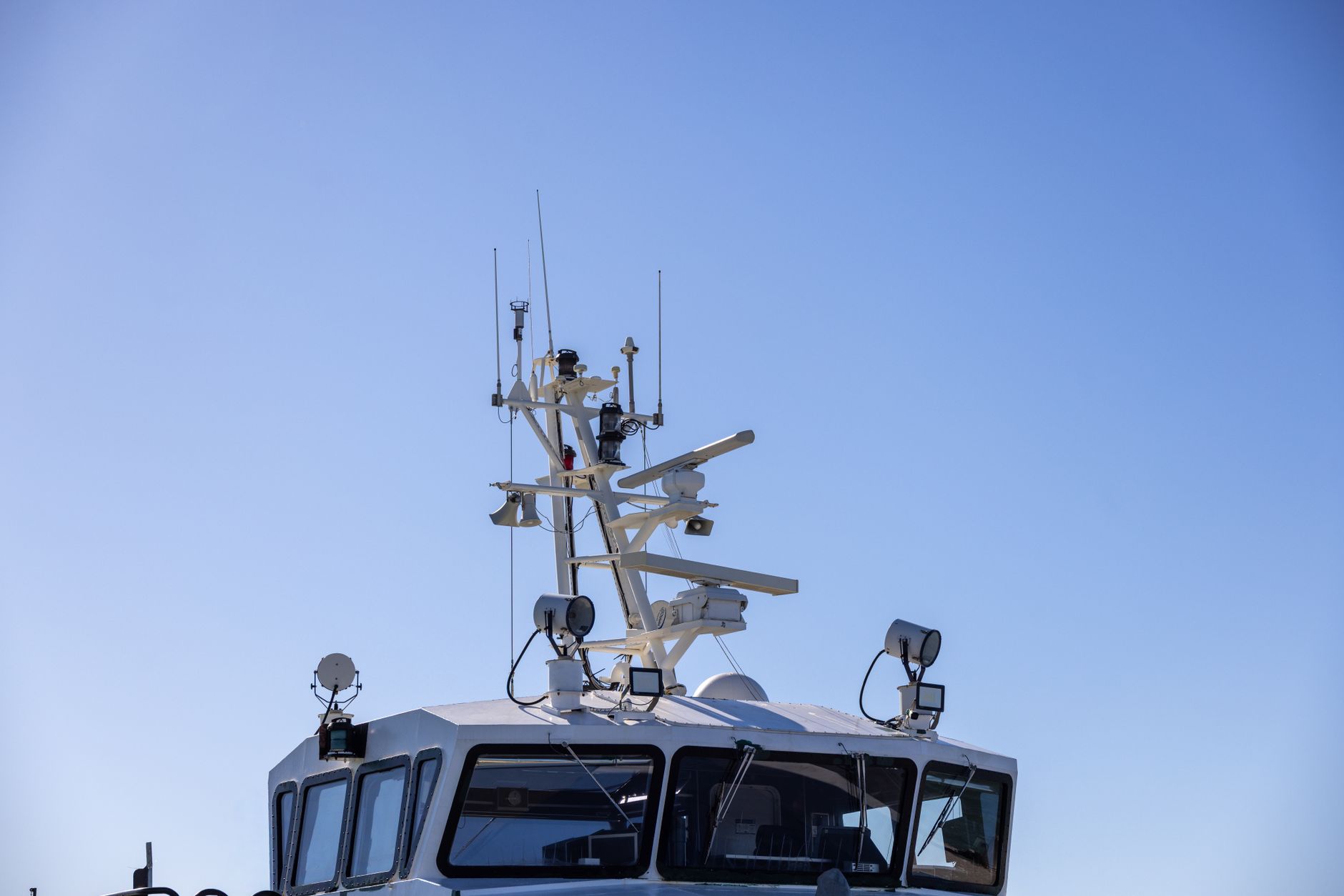 a fleet of military radar tracking dishes arranged in a row on a flat concrete installation, set against a clear blue sky