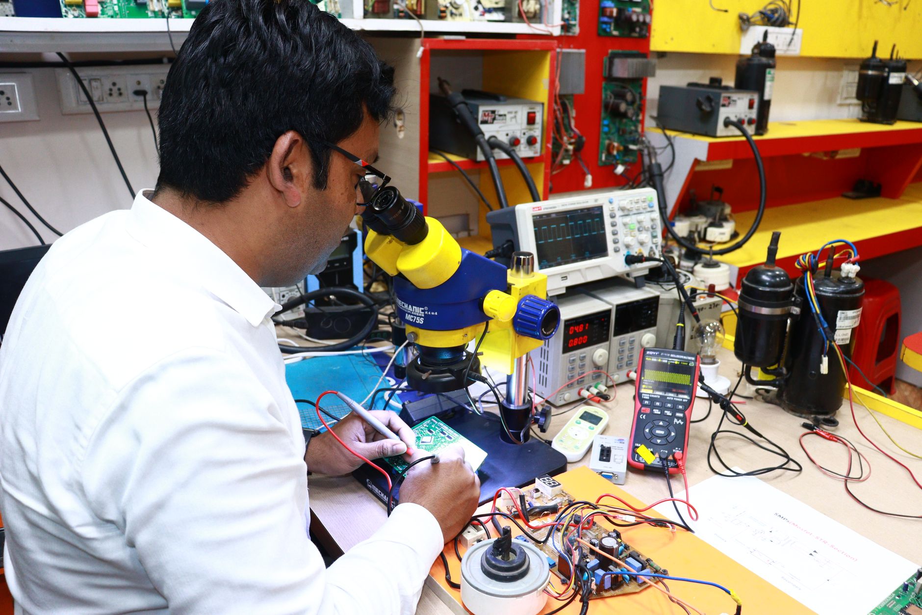 interior of a hardware engineering laboratory with circuit boards, oscilloscopes, and shielded testing equipment arranged on metal workbenches