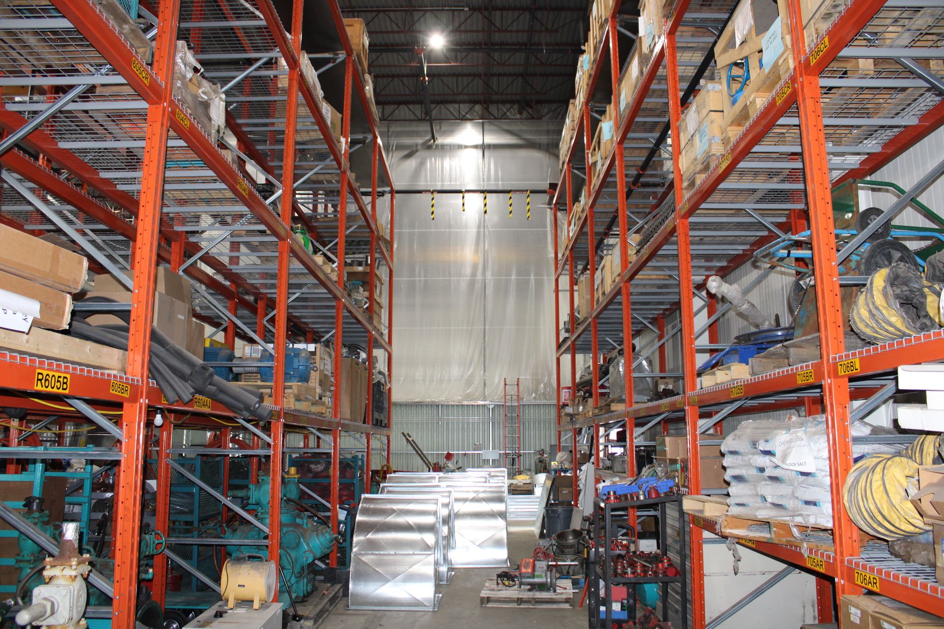 rows of sealed shipping pallets bearing produce labels in a large cold-storage warehouse facility