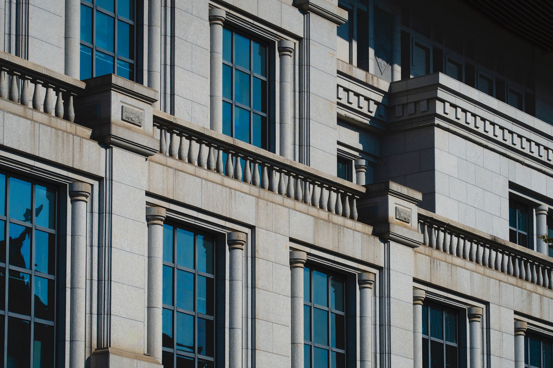 exterior of the Bank of Japan's historic stone headquarters building in central Tokyo, late afternoon light casting shadows across the facade