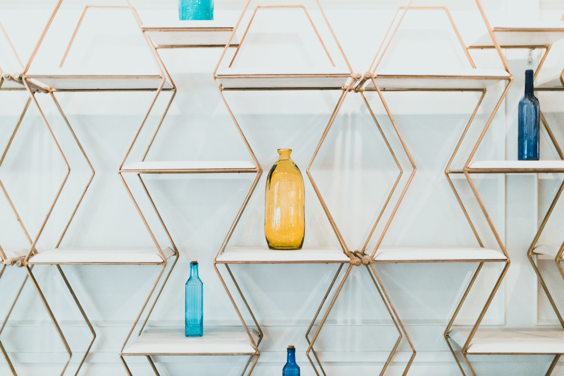 rows of glass perfume and grooming bottles arranged on a white retail shelf with soft ambient lighting