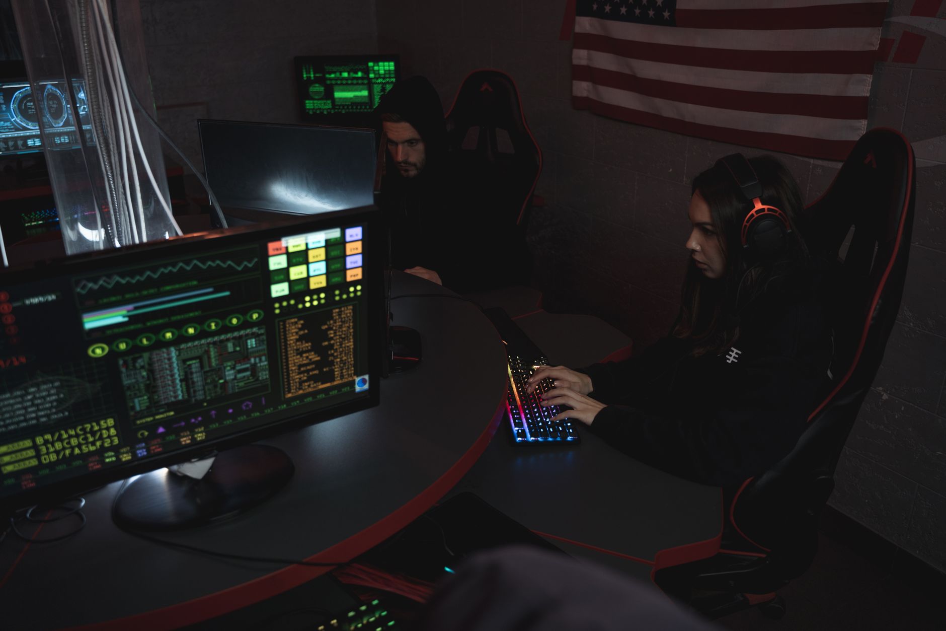 rows of computer workstations inside a cybersecurity operations center with glowing dashboard displays