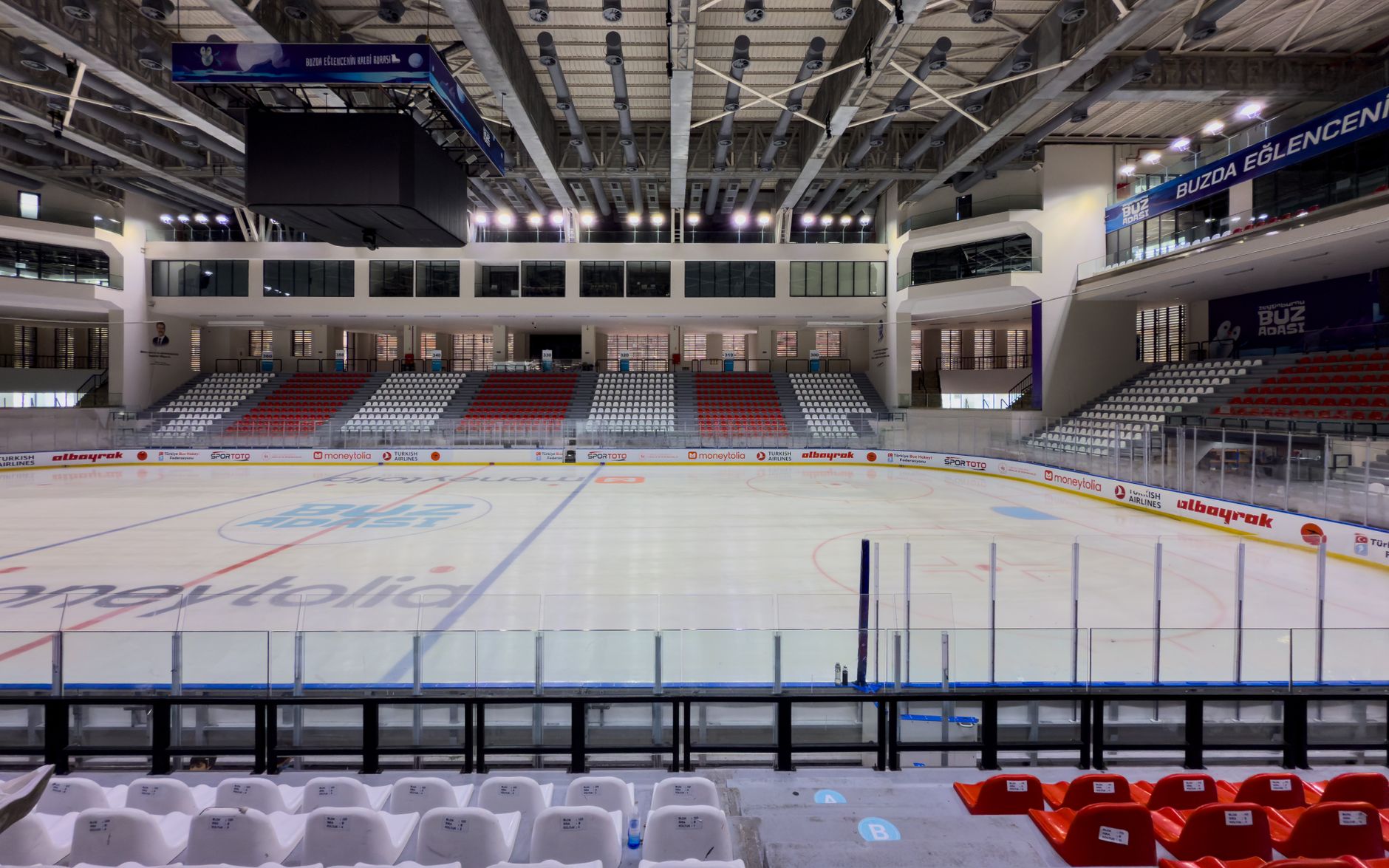 wide-angle view of a modern sports arena interior at night with empty seats and arena lighting casting a warm glow across the court floor