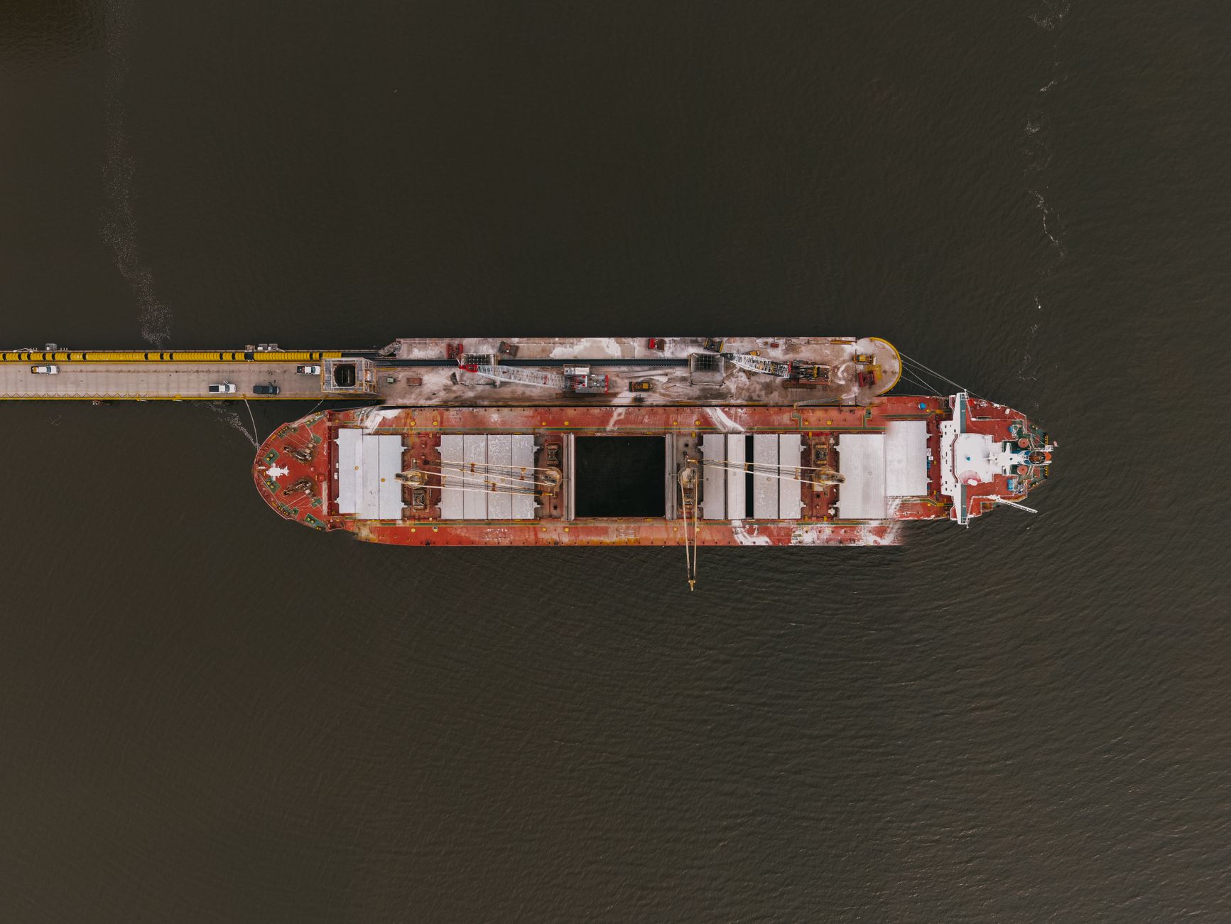 aerial view of a cable-laying ship docked at a port with large fiber optic cable drums on its rear deck