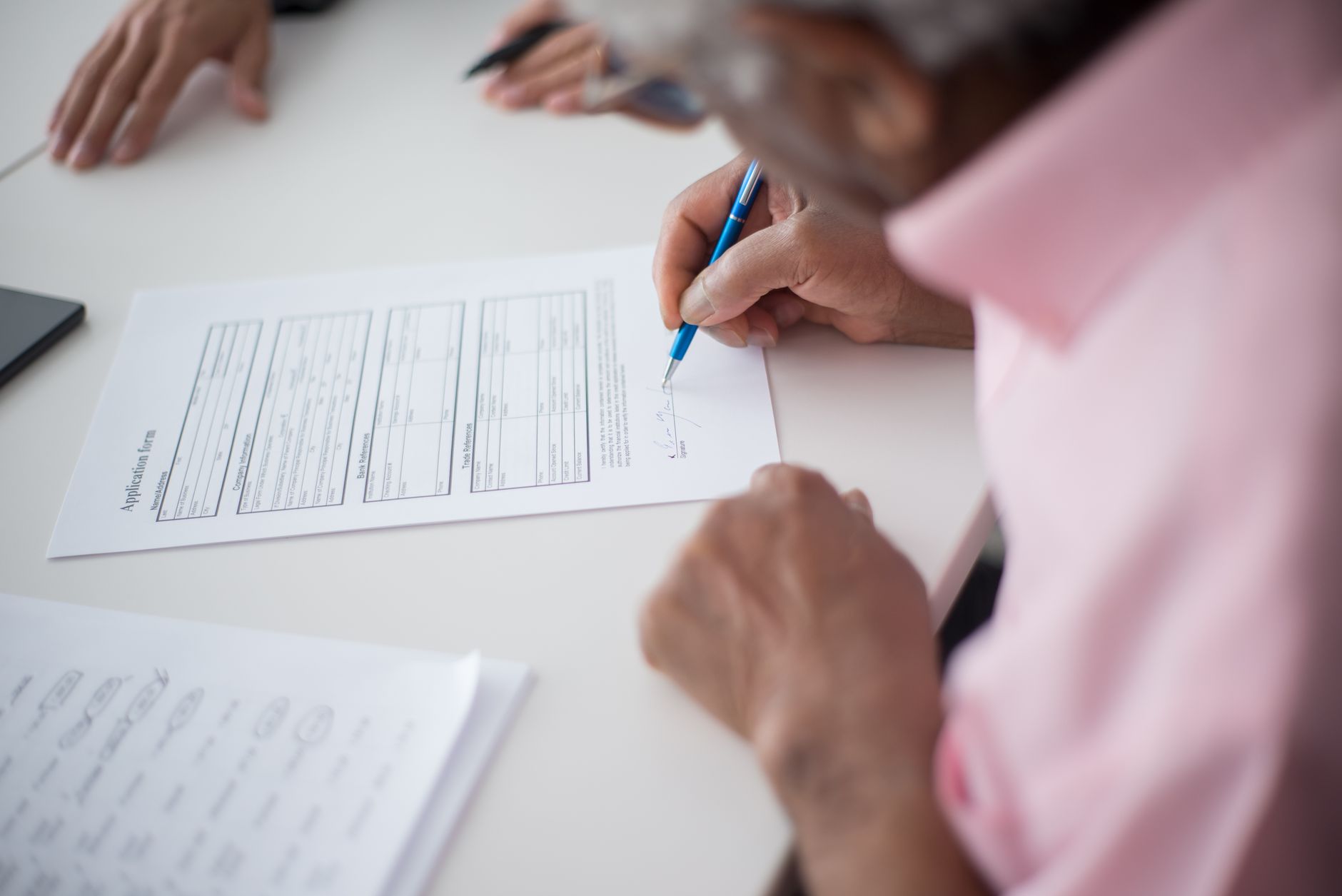 close-up of a residential mortgage application form on a desk beside a set of house keys and a pen, natural light from a nearby window