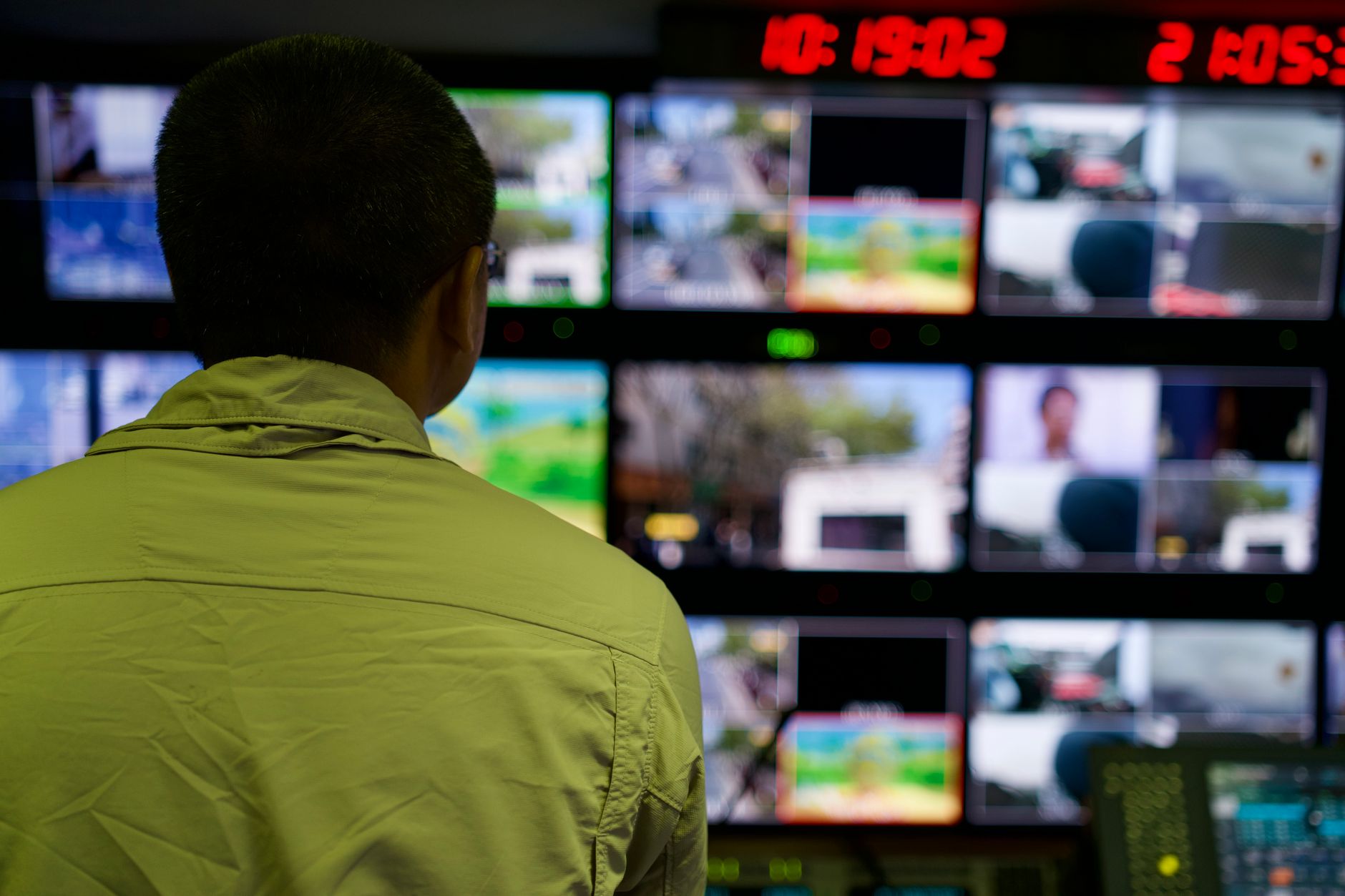 a wide-angle shot of a modern open-plan social media operations centre with multiple large monitoring screens displaying platform analytics and content dashboards