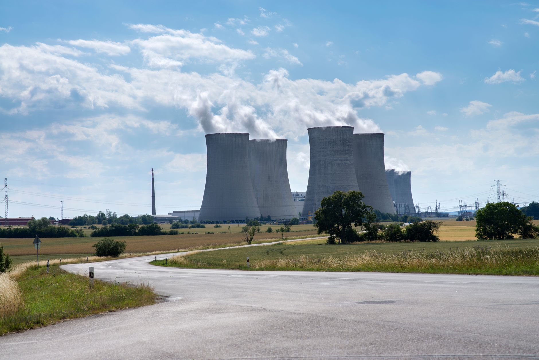 exterior of a large semiconductor fabrication facility at dusk, with industrial cooling towers and a vast parking lot in the foreground