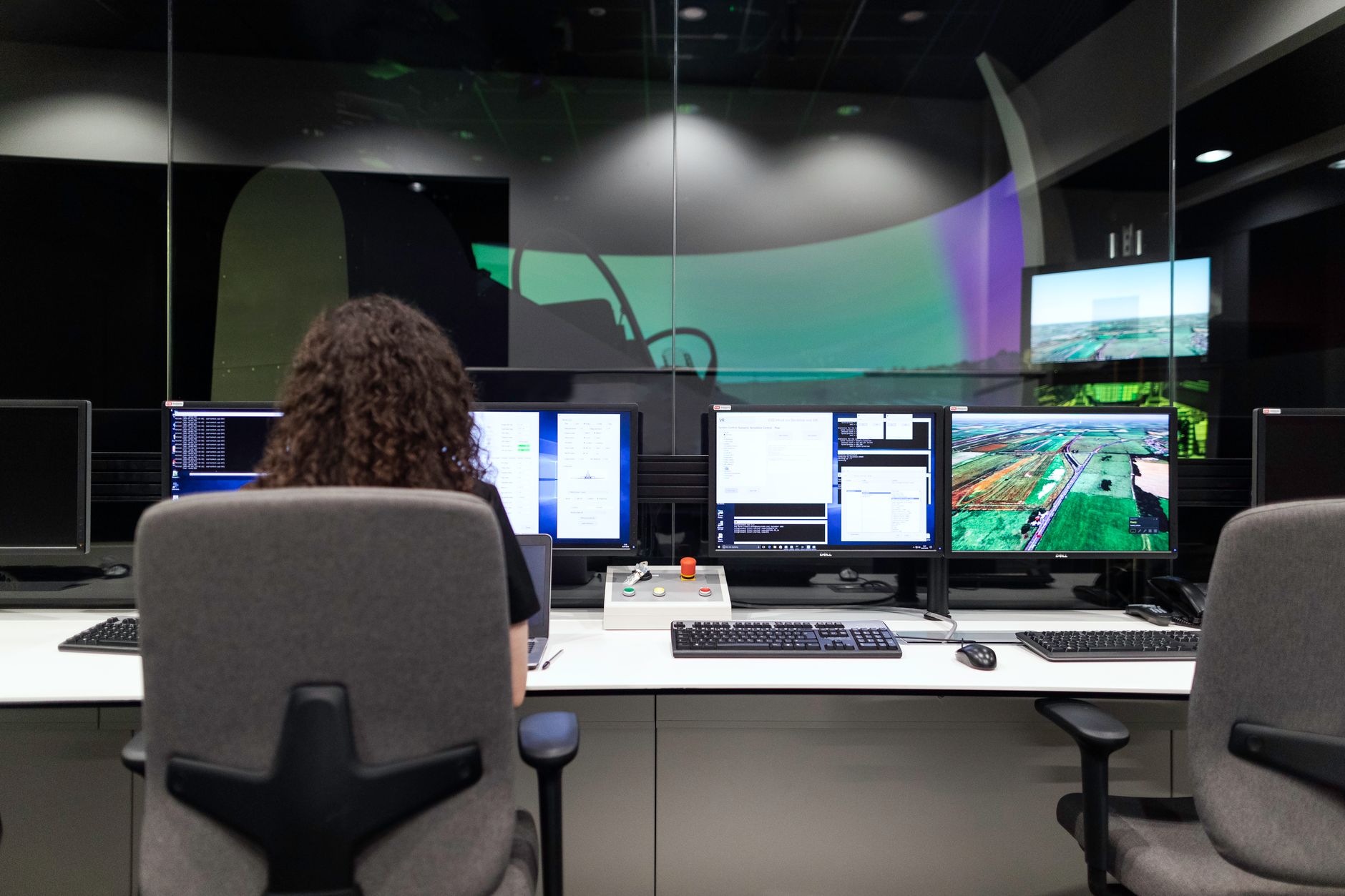 a modern open-plan technology office interior at night with glowing workstation monitors displaying network topology diagrams and data flow visualisations