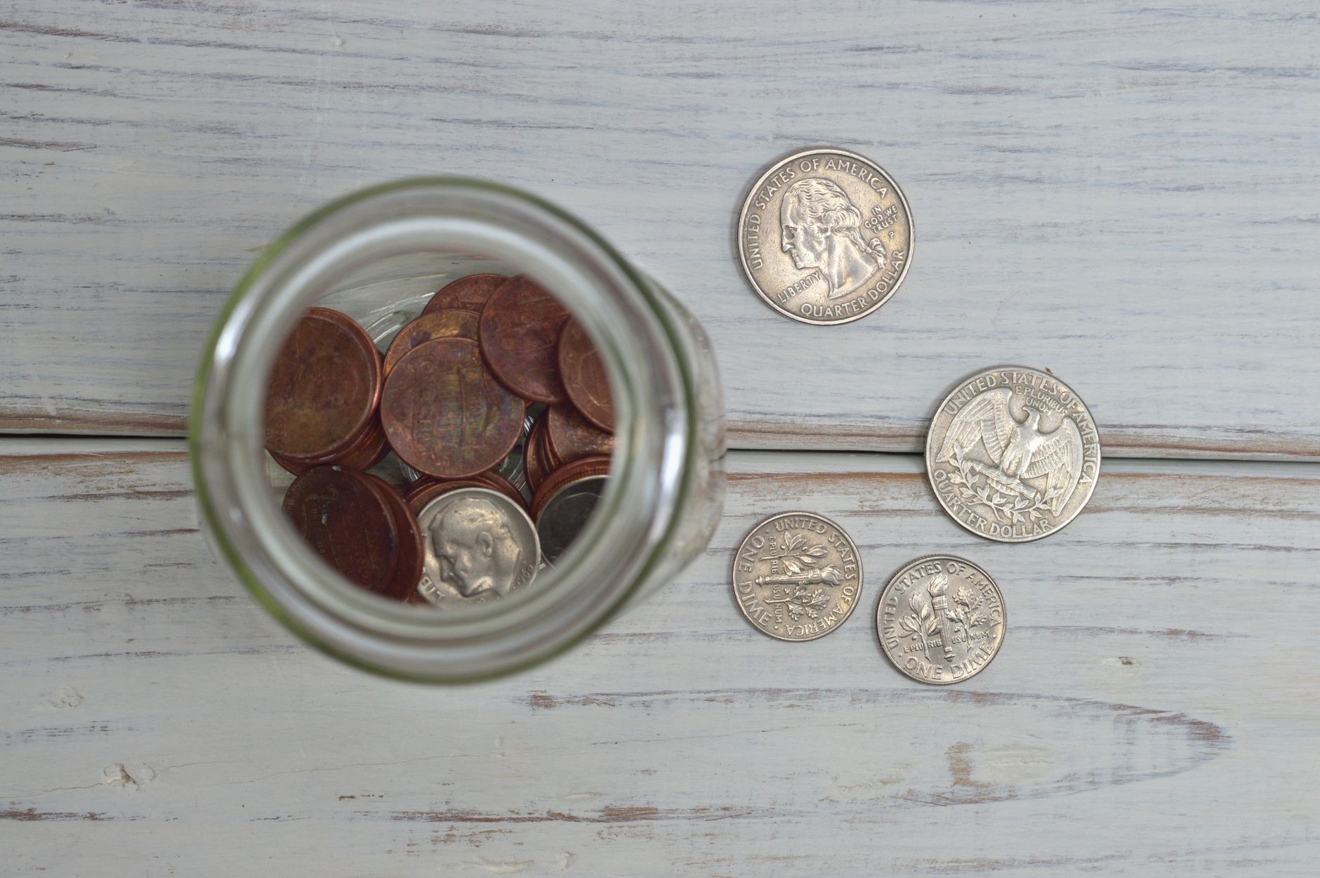 a glass jar filled with coins and paper currency sitting on a wooden surface beside a printed retirement planning worksheet