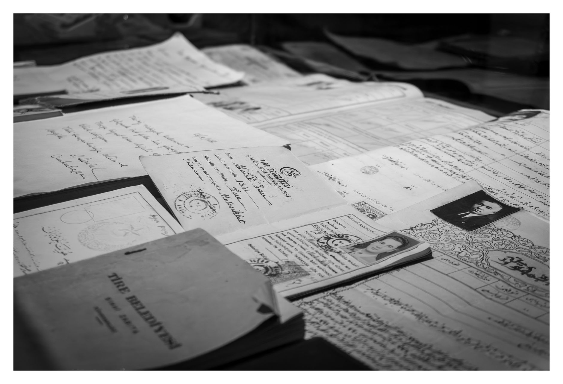 close-up of weathered bond certificates and ledger books inside a glass museum display case, with soft directional lighting highlighting the aged paper textures