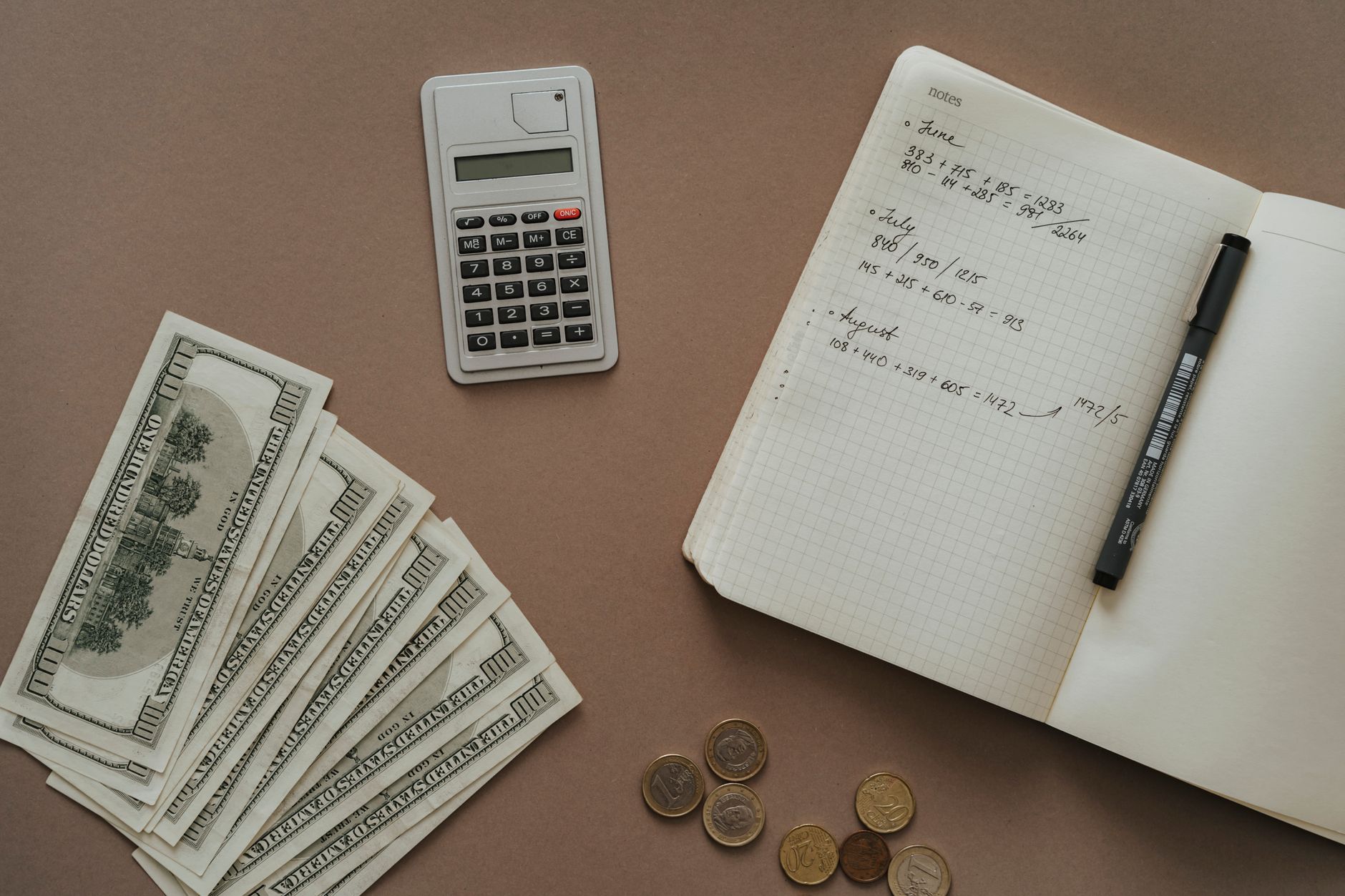 close-up of a monthly household budget ledger open on a wooden kitchen table, pencil resting beside handwritten expense columns