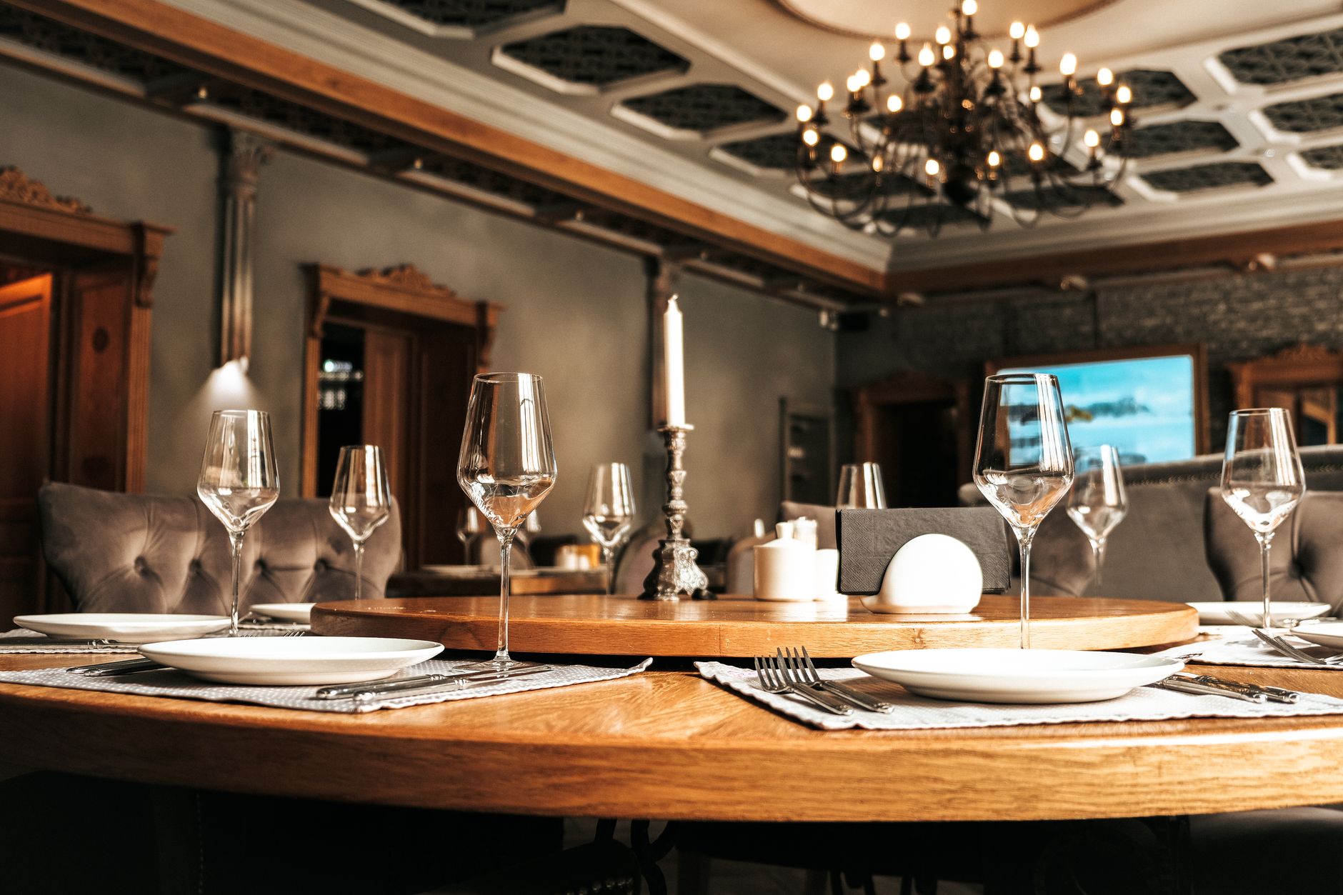 wide-angle view of a formal state dining room set for a large diplomatic dinner, with white linen tablecloths and crystal glassware arranged under soft chandeliers