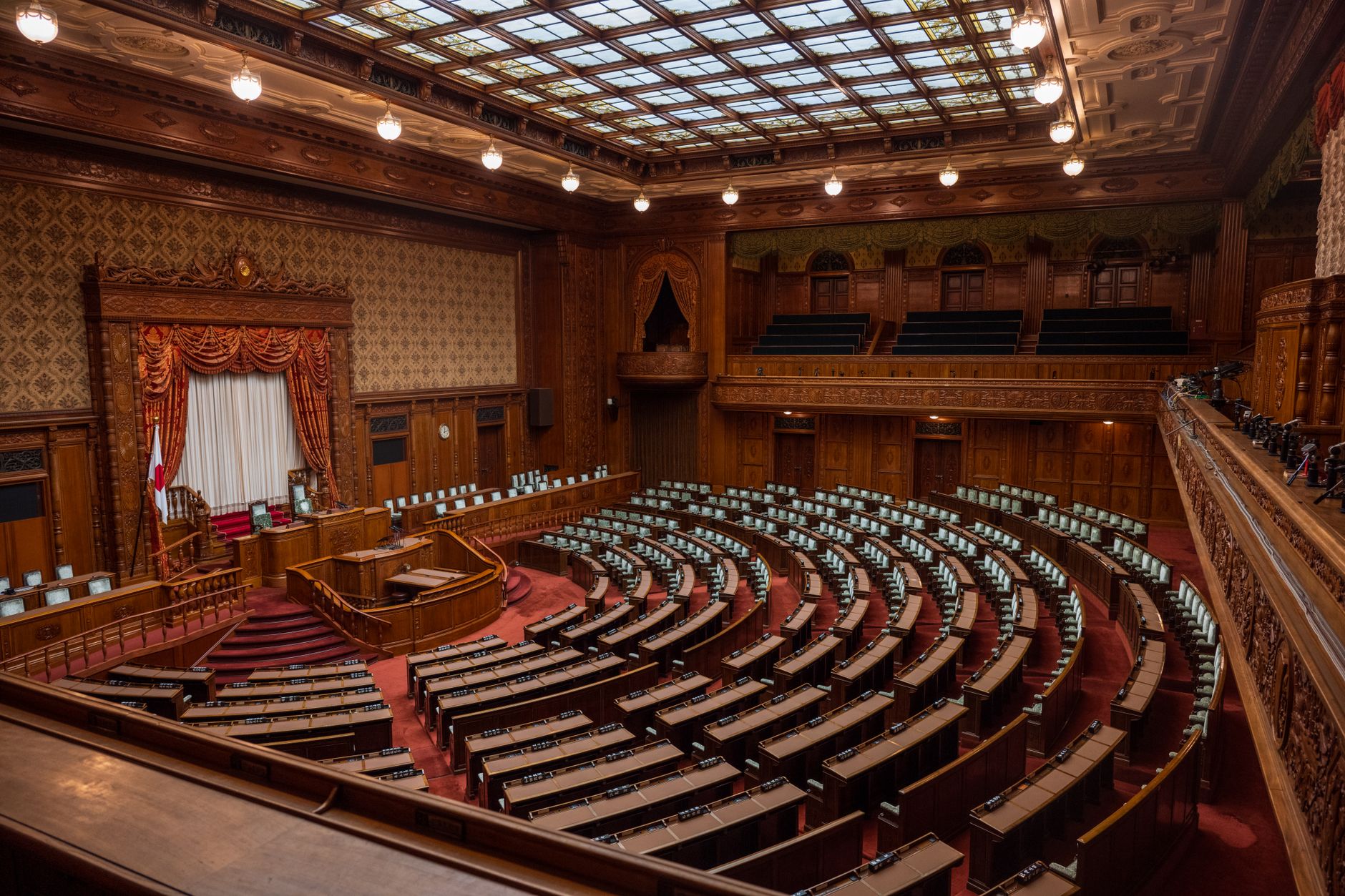 interior of an empty U.S. Senate committee hearing chamber with rows of curved wooden desks under warm overhead lighting, no people present