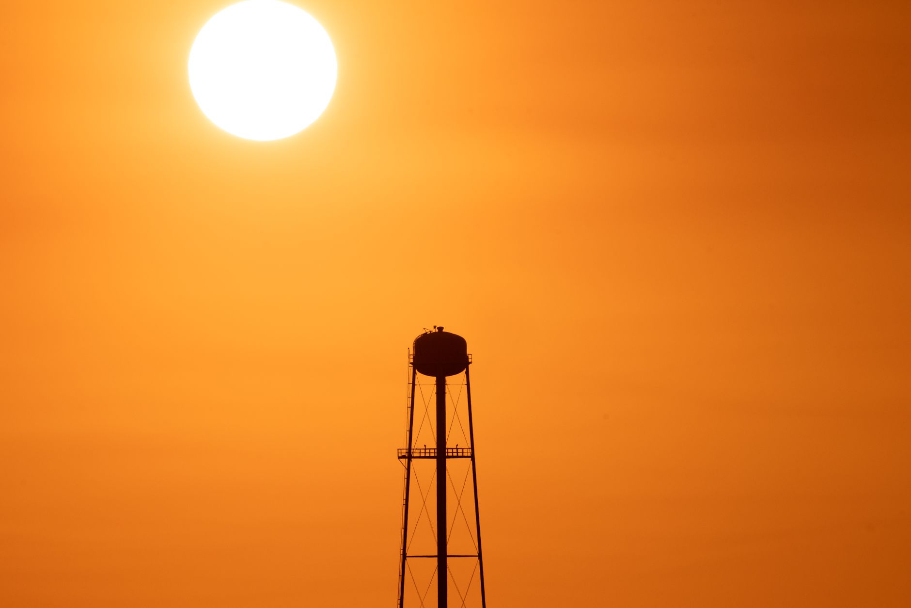 exterior of a large film studio lot at dusk, with production warehouses and a water tower visible against an orange sky