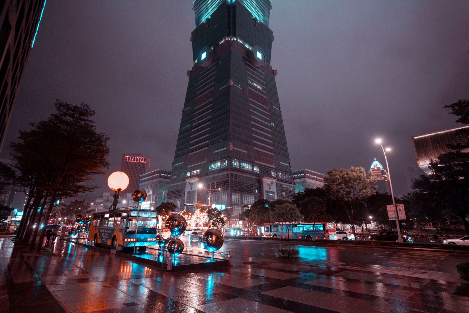 exterior facade of a modern financial technology office building at night with lit windows reflecting on wet pavement
