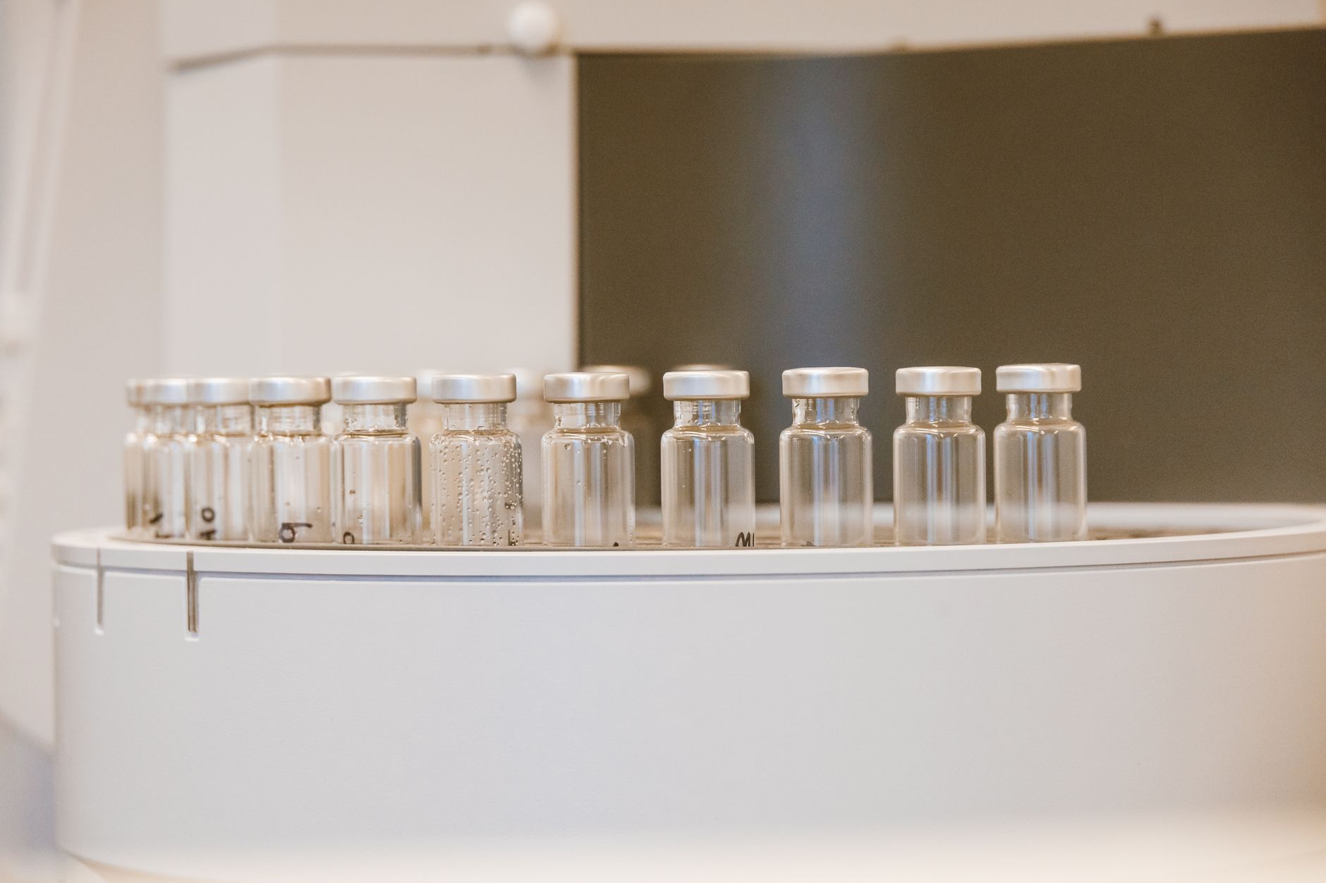 Close-up of a laboratory bioreactor system used for plant-based protein cultivation, with rows of transparent culture vessels illuminated under controlled white lighting in a sterile research facility