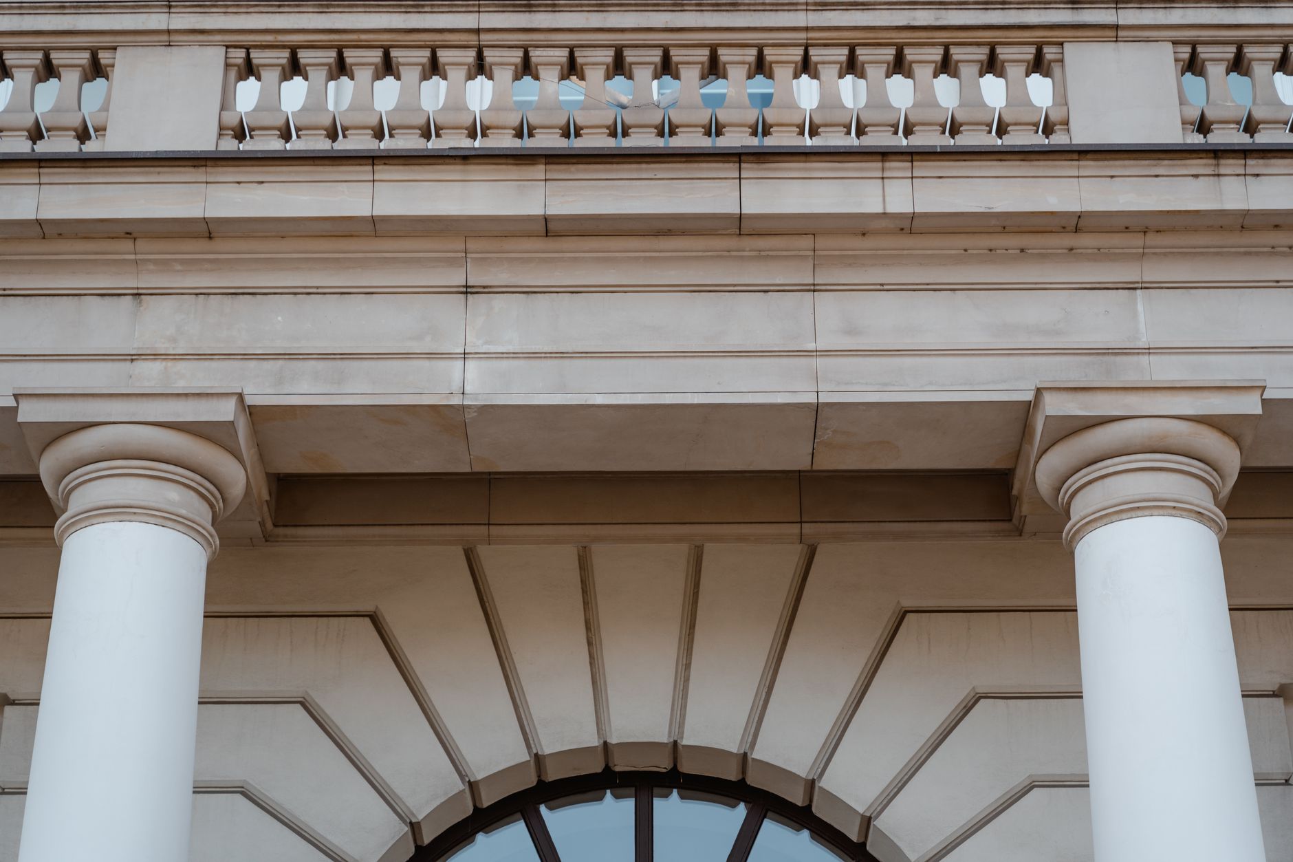 exterior of a large government administrative building with grey concrete columns and a modest queue of people visible near the entrance, taken on an overcast London afternoon