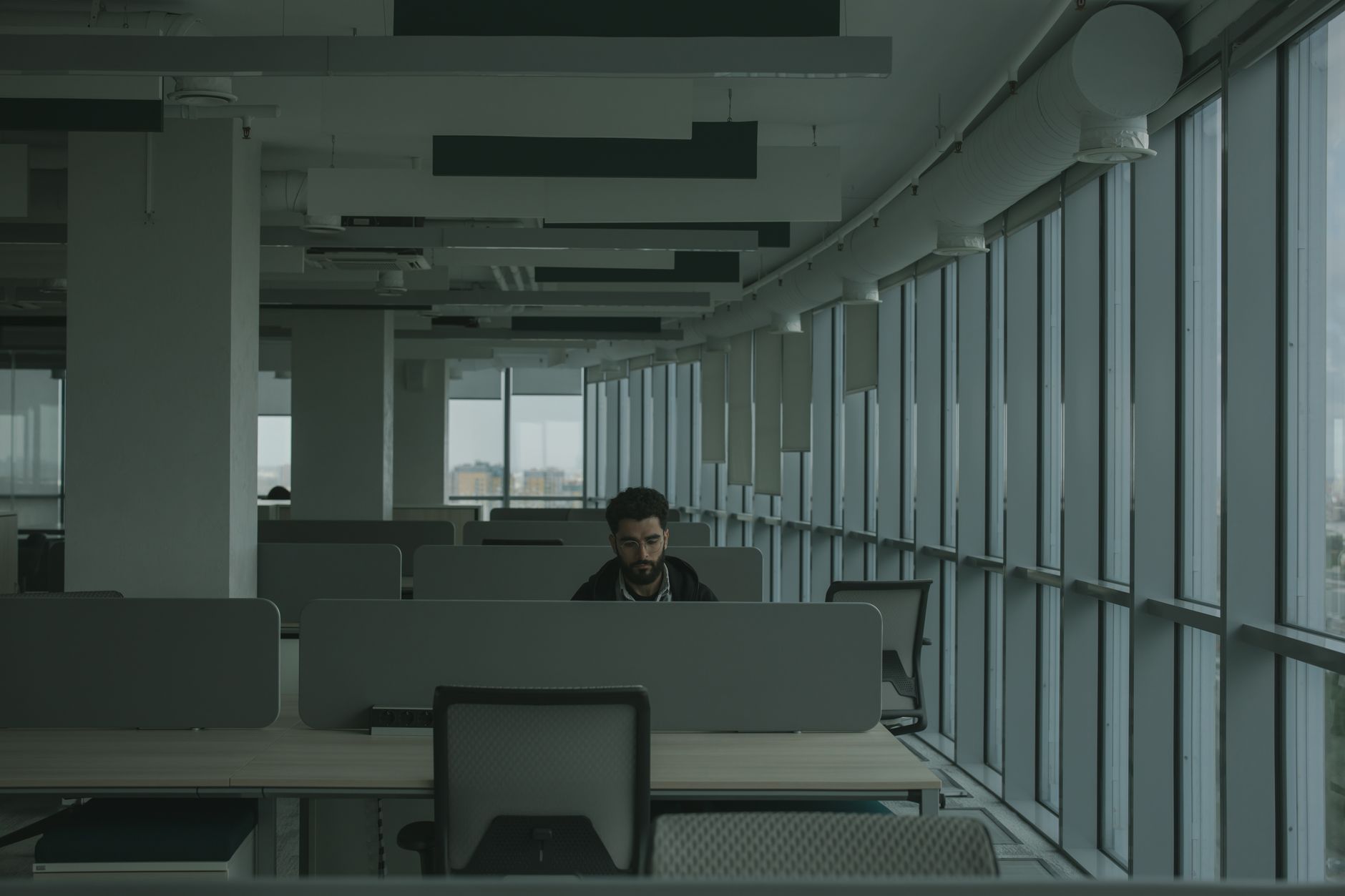 rows of empty office cubicles inside a job centre with fluorescent lighting and information leaflets stacked on countertops