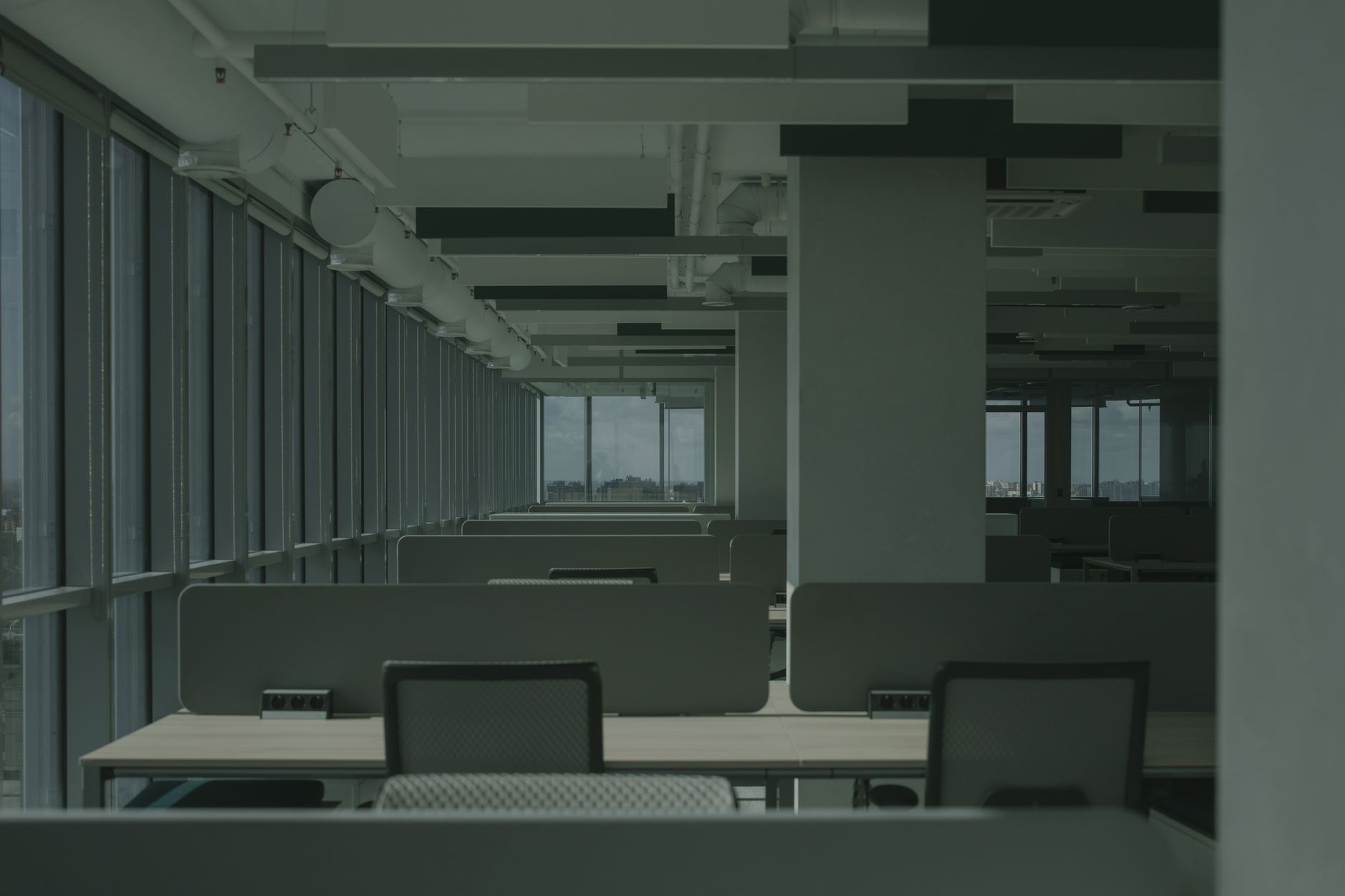 empty open-plan office interior with rows of unoccupied desks bathed in natural light from floor-to-ceiling windows