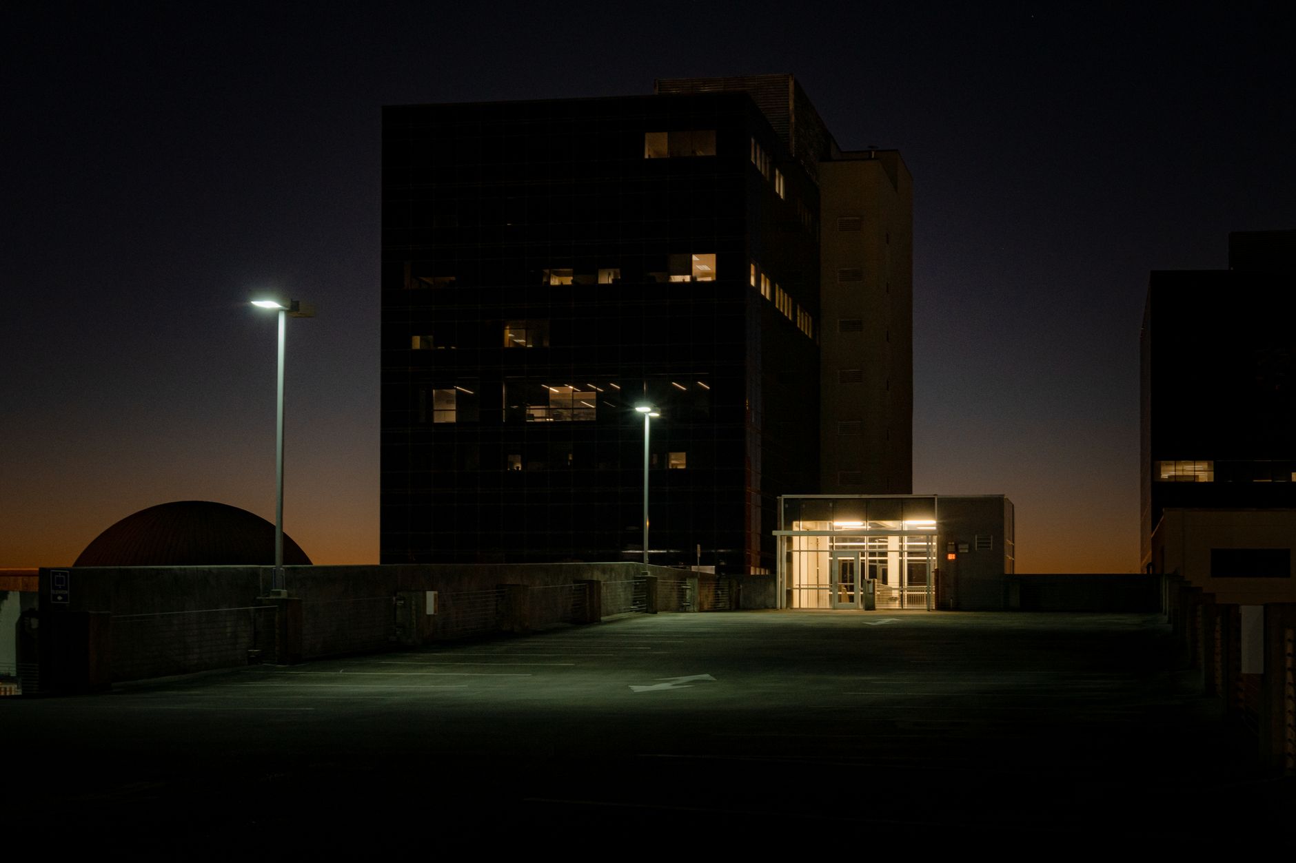 exterior of a modern technology campus at dusk with illuminated glass facades and empty parking lots