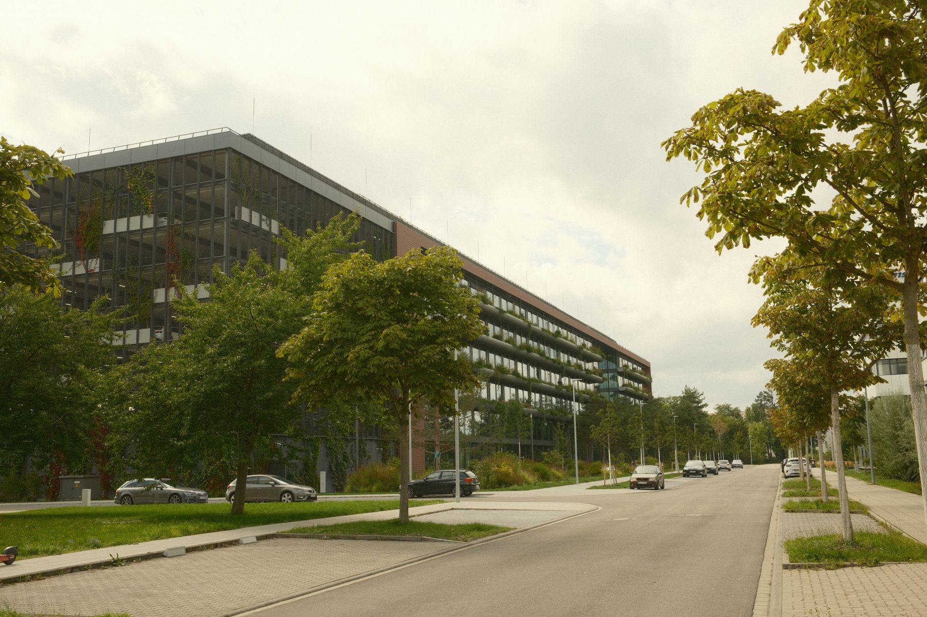 exterior of a large modern corporate office building in a suburban business park, with glass facades and a manicured forecourt under overcast skies