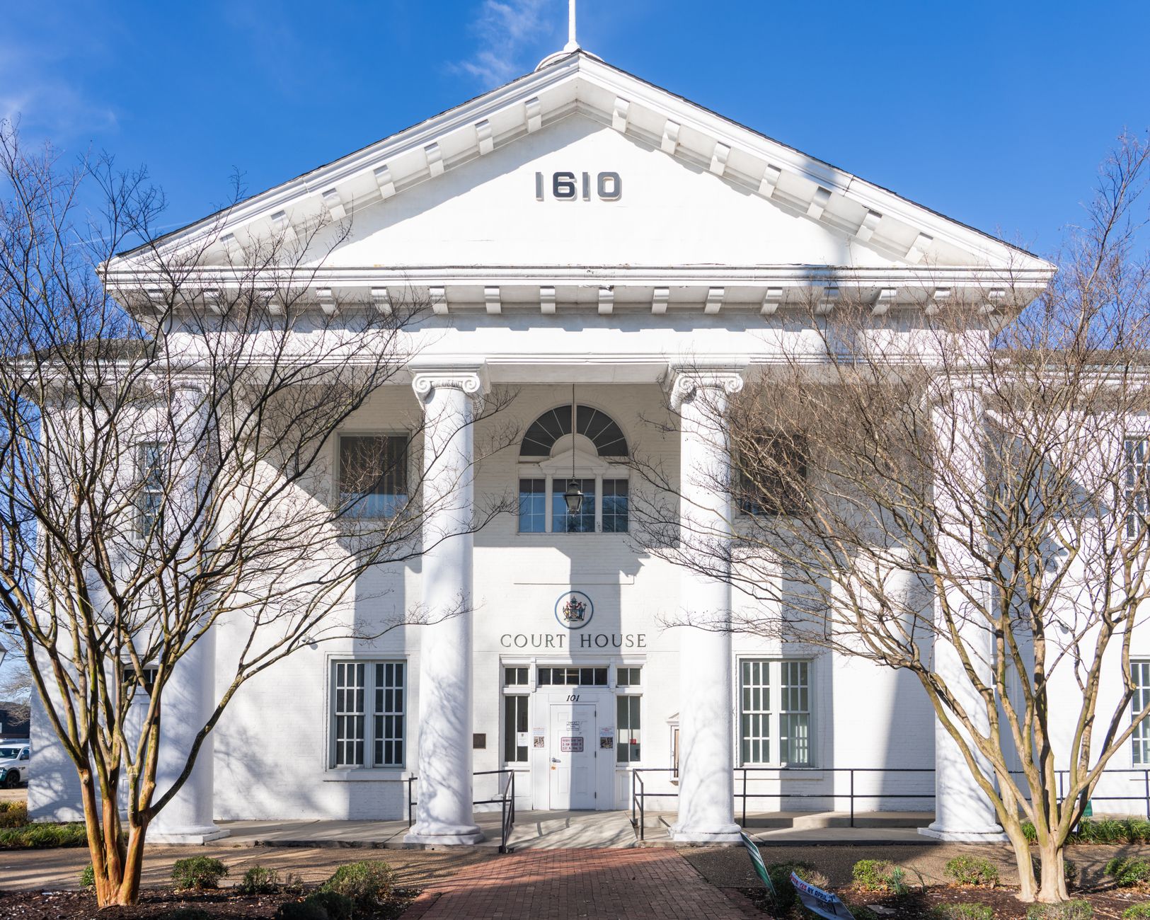 Exterior of a county courthouse with stone steps and a row of columns, surrounded by autumn trees