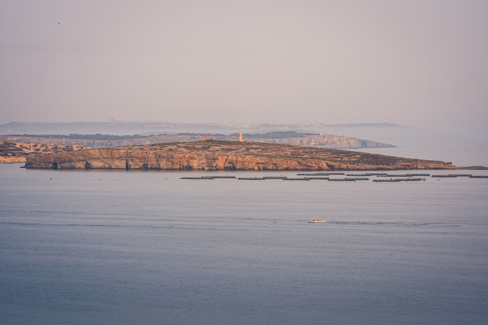 aerial view of supertankers navigating a narrow strait at dawn, with distant coastline visible on both sides
