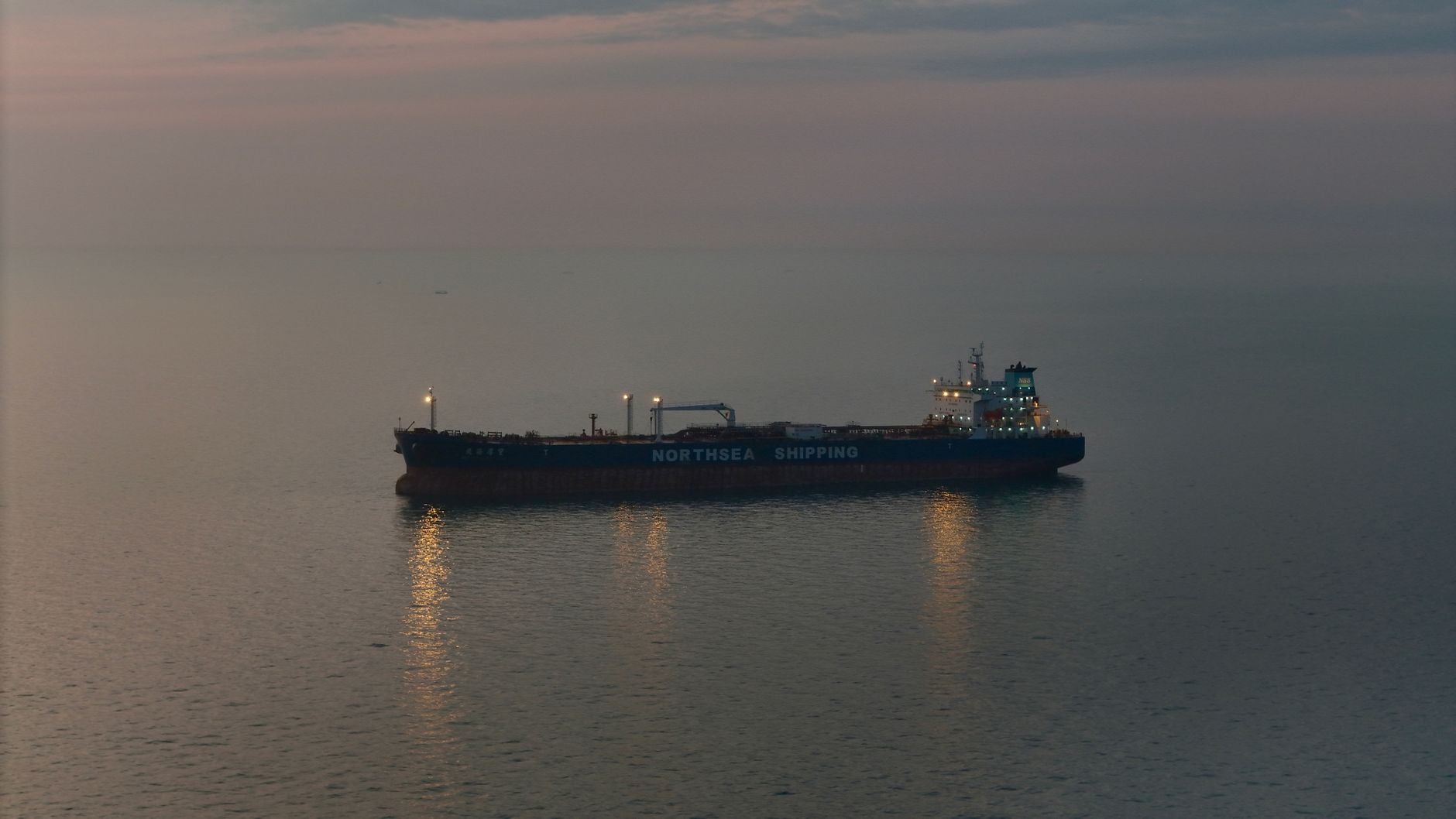 aerial view of oil tankers anchored in calm waters near a narrow strait, no text or logos visible