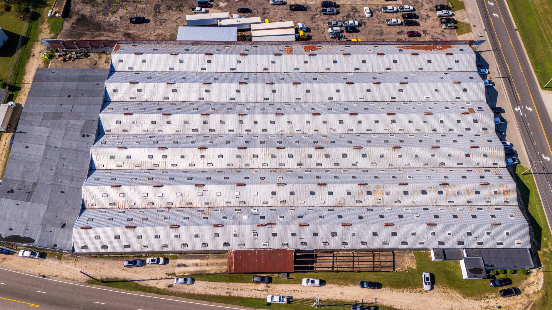 aerial view of a large military logistics base with rows of armored vehicles and supply infrastructure under open sky