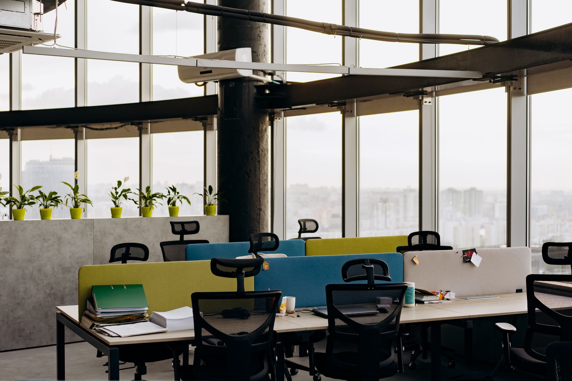 interior of a modern startup office space in Tel Aviv, open-plan workstations with monitors displaying code, large windows overlooking the city