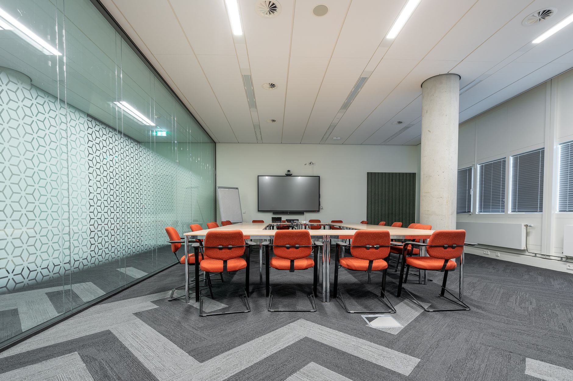 interior of a venture capital conference room in a modern coworking space, with large wall-mounted screens displaying funding pipeline charts and a cityscape visible through floor-to-ceiling windows