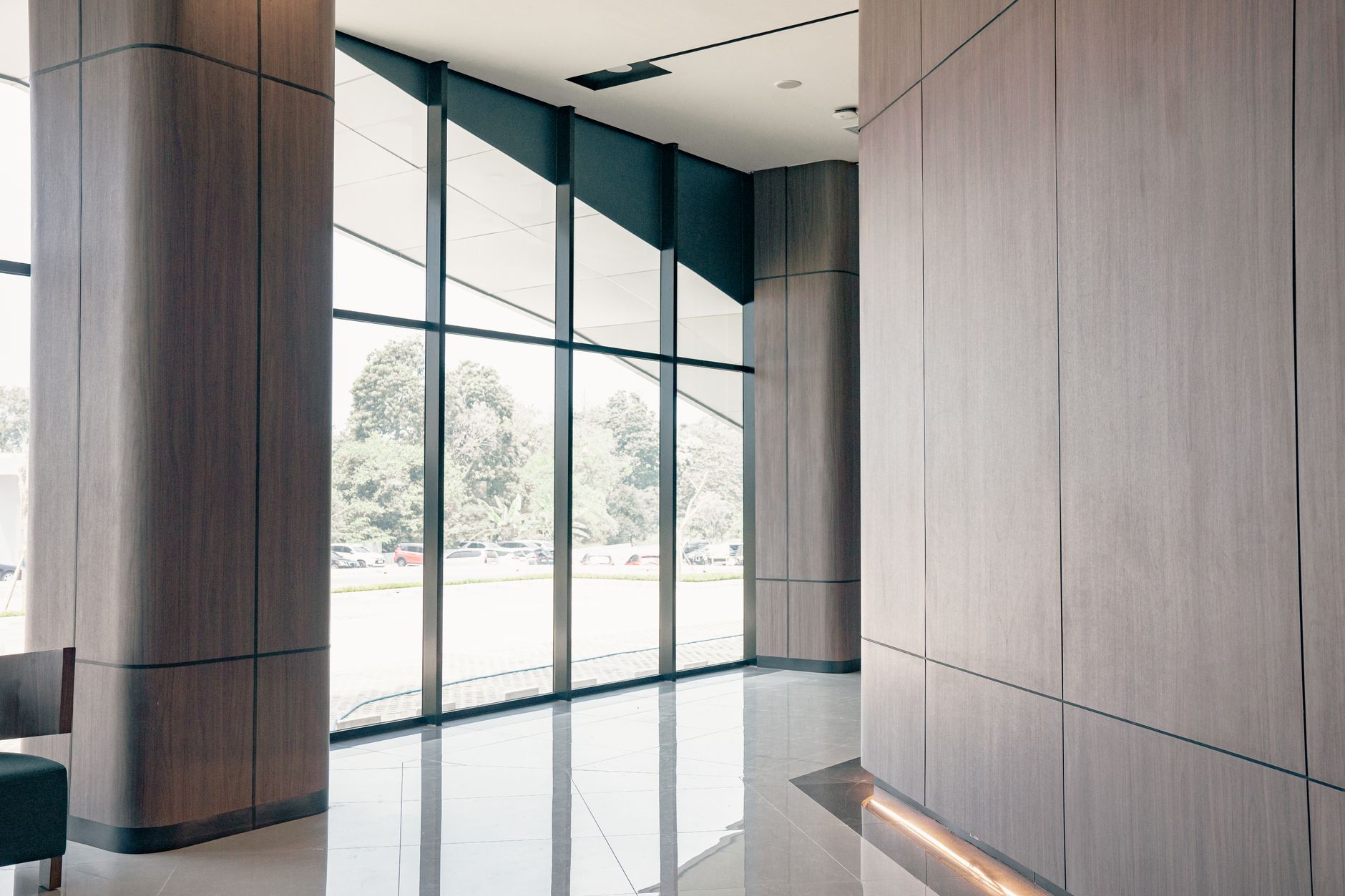 exterior view of a glass-fronted private equity office building in Miami's Coconut Grove district, empty lobby visible through floor-to-ceiling windows at midday