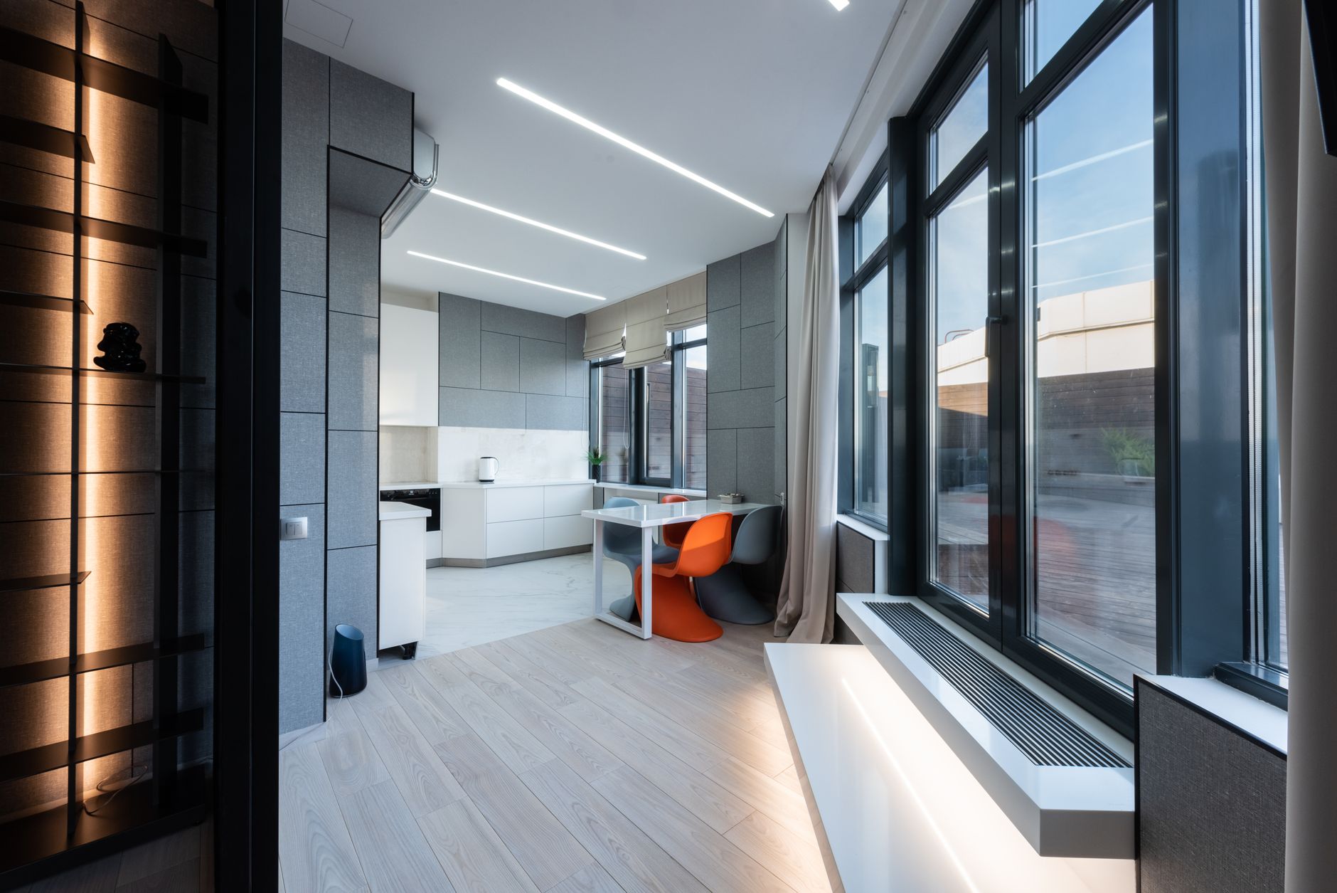 Interior of a partially completed luxury apartment shell, featuring floor-to-ceiling window frames overlooking a dense urban skyline
