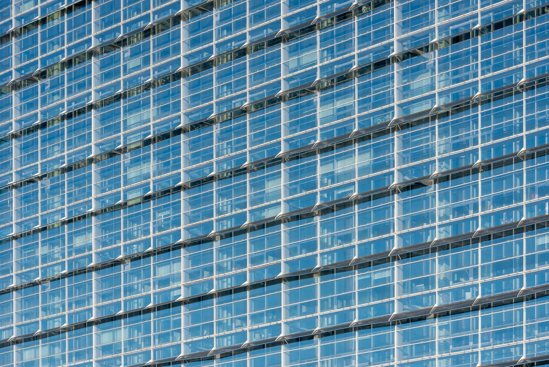 exterior of a modern Tel Aviv office tower at midday, glass facade reflecting urban streetscape below