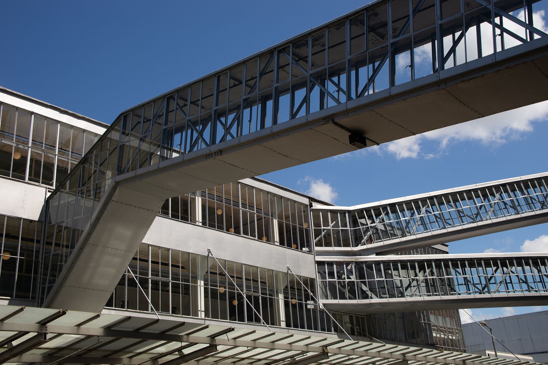 exterior of a glass-fronted technology company building at midday, with a corporate campus walkway and manicured grounds visible in the foreground